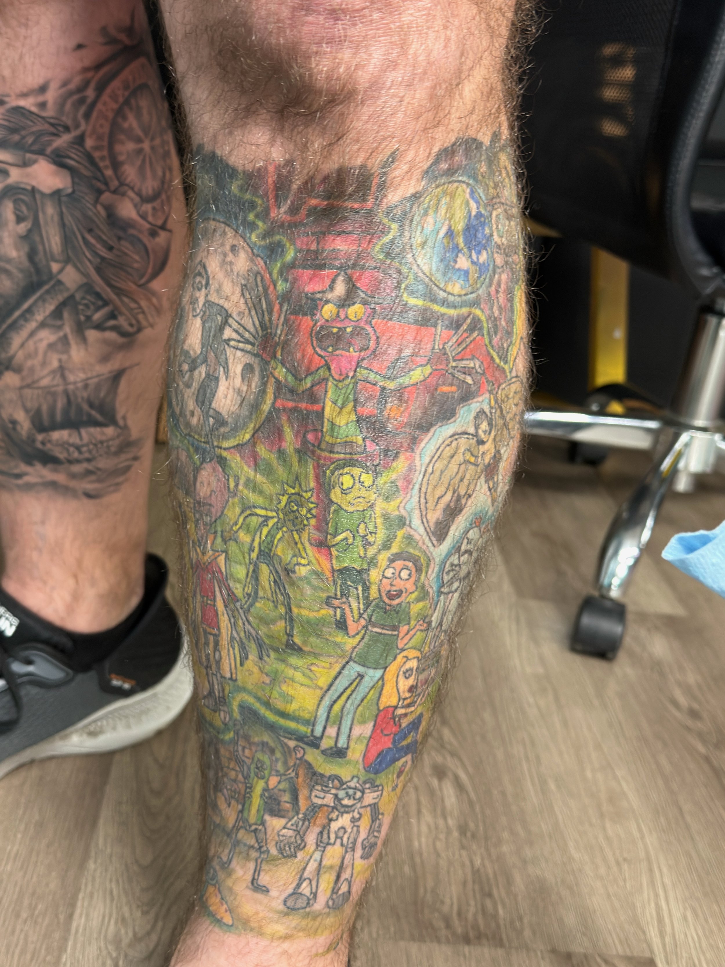 Sioux Falls South Dakota Tattoo Shop. Apex Ink. Colorful tattoo sleeve on a man's leg featuring characters and scenes from the animated TV show Rick and Morty.