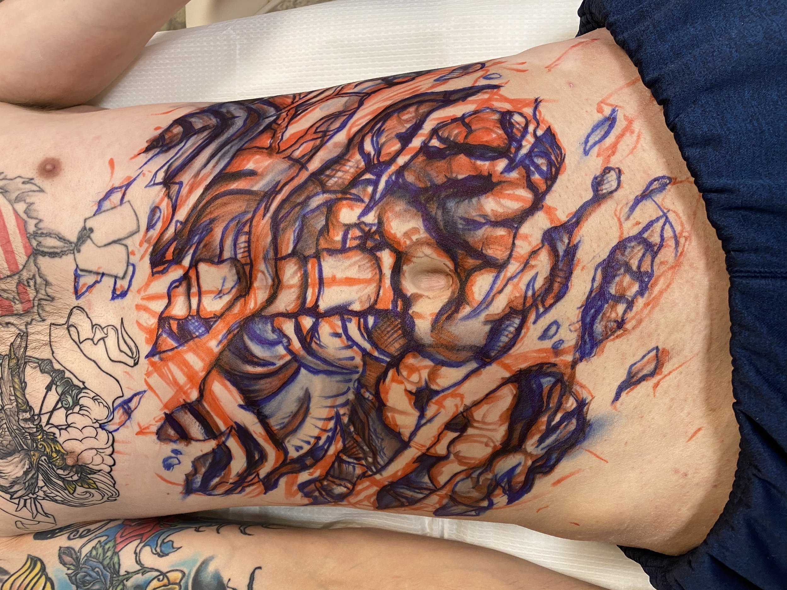 Tattoo artist in the process of creating a large, colorful tattoo on a person's chest, depicting a detailed dinosaur skeleton in a sketch style with red and blue ink.