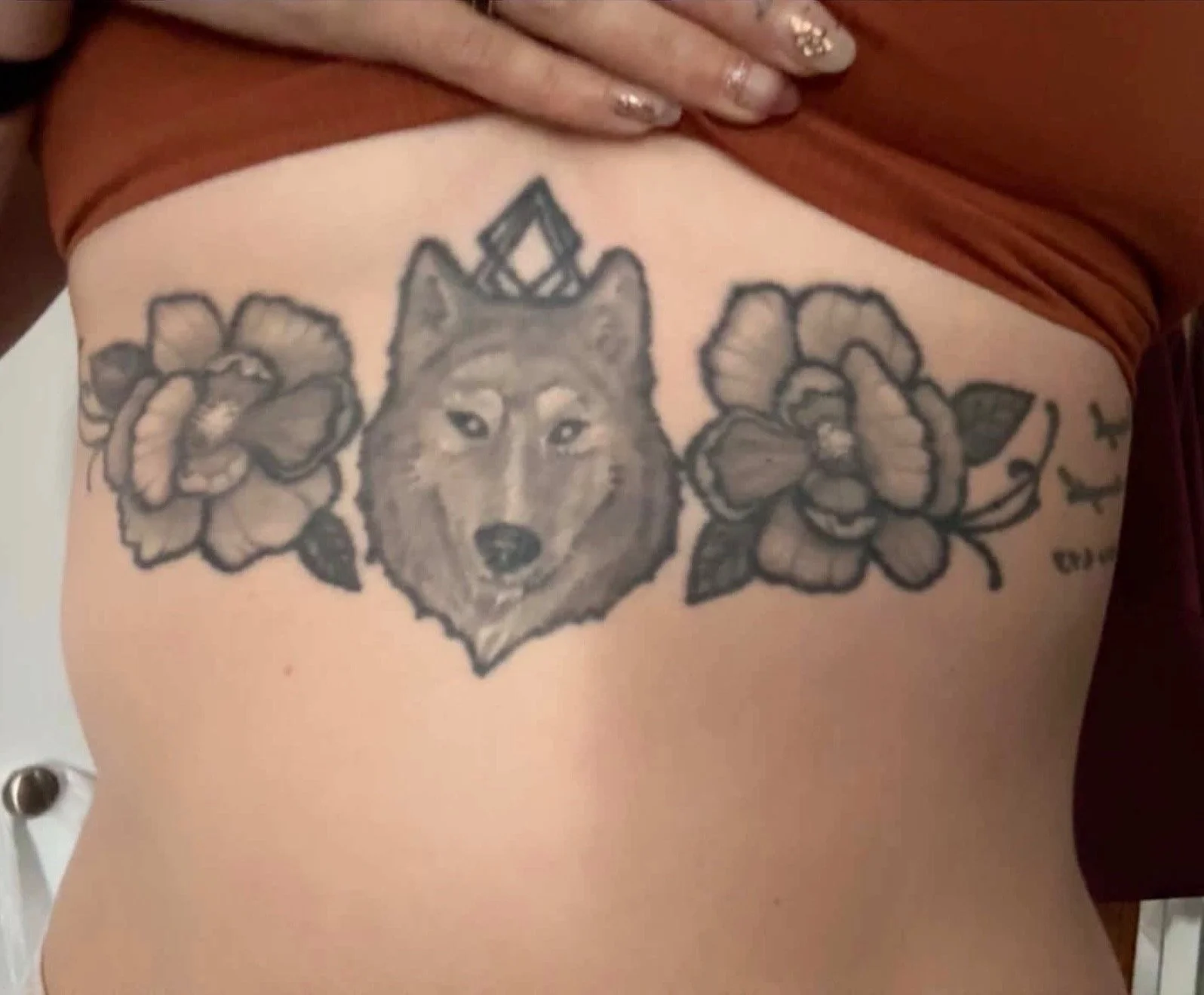 Sioux Falls South Dakota Tattoo Shop. Apex Ink. Tattoo of a wolf's face flanked by two large flowers on each side on a person's side.