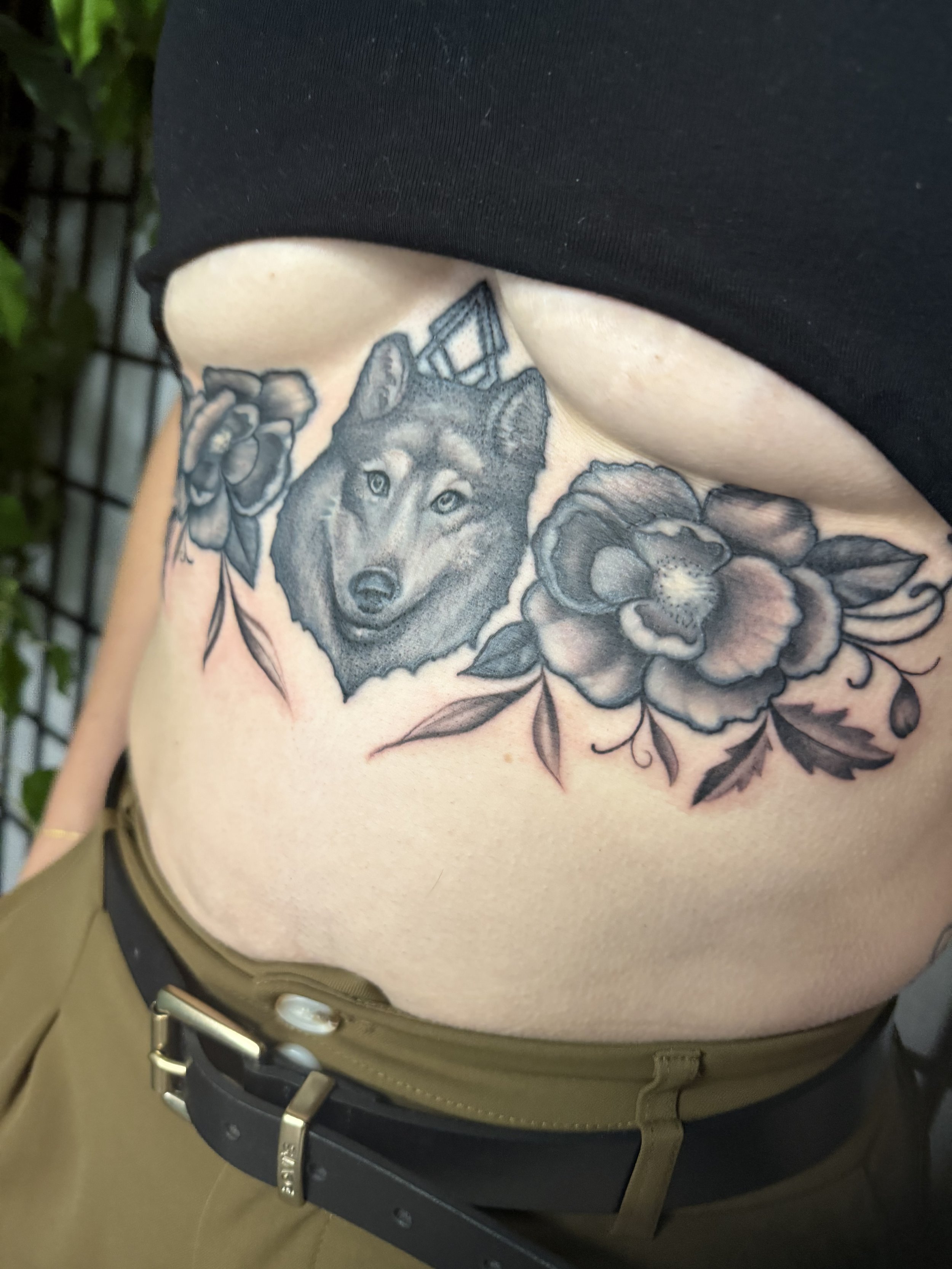 Sioux Falls South Dakota Tattoo Shop. Apex Ink. Tattoo of a wolf's head surrounded by floral designs on someone's side torso.