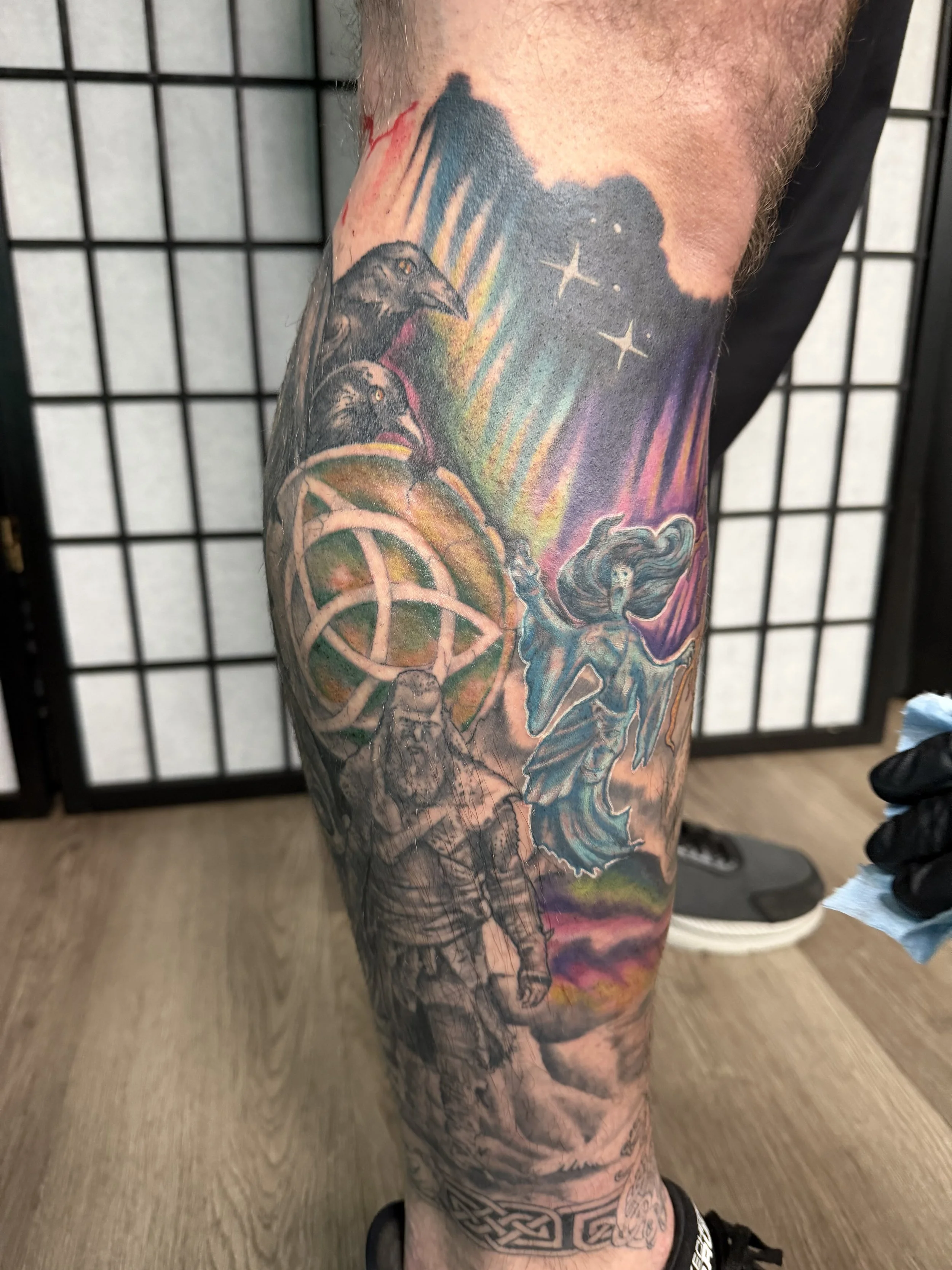 Sioux Falls South Dakota Tattoo Shop. Apex Ink. Tattoo sleeve featuring a blue dragon, a woman casting a spell, a Viking, owls, stars, and a colorful sky.