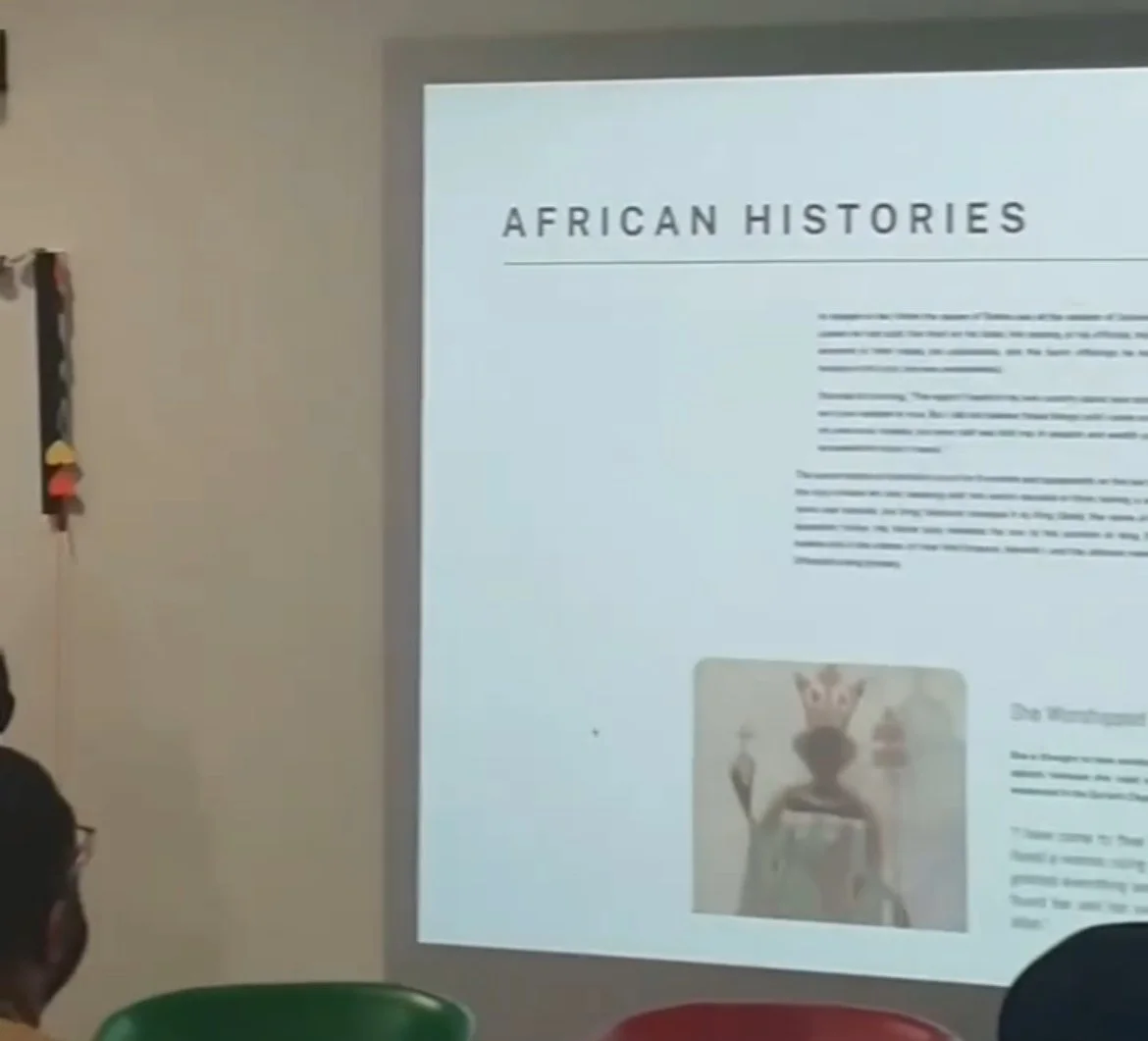 A presentation slide titled 'African Histories' displayed on a projection screen in a classroom. Part of the audience is visible in the foreground, and decorations are on the wall to the left.