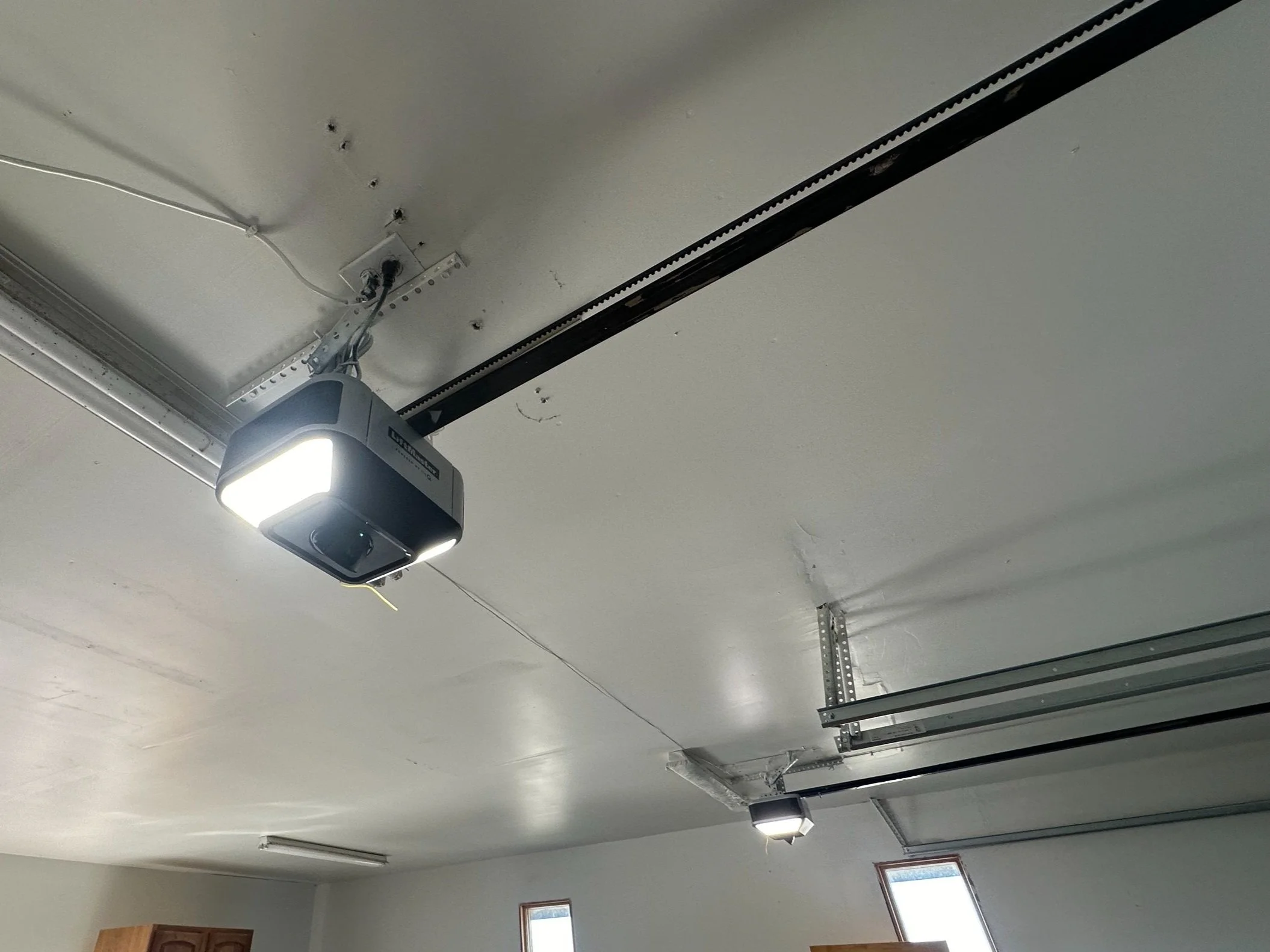 Garage ceiling with two installed overhead garage door openers and tracks, some wiring visible.