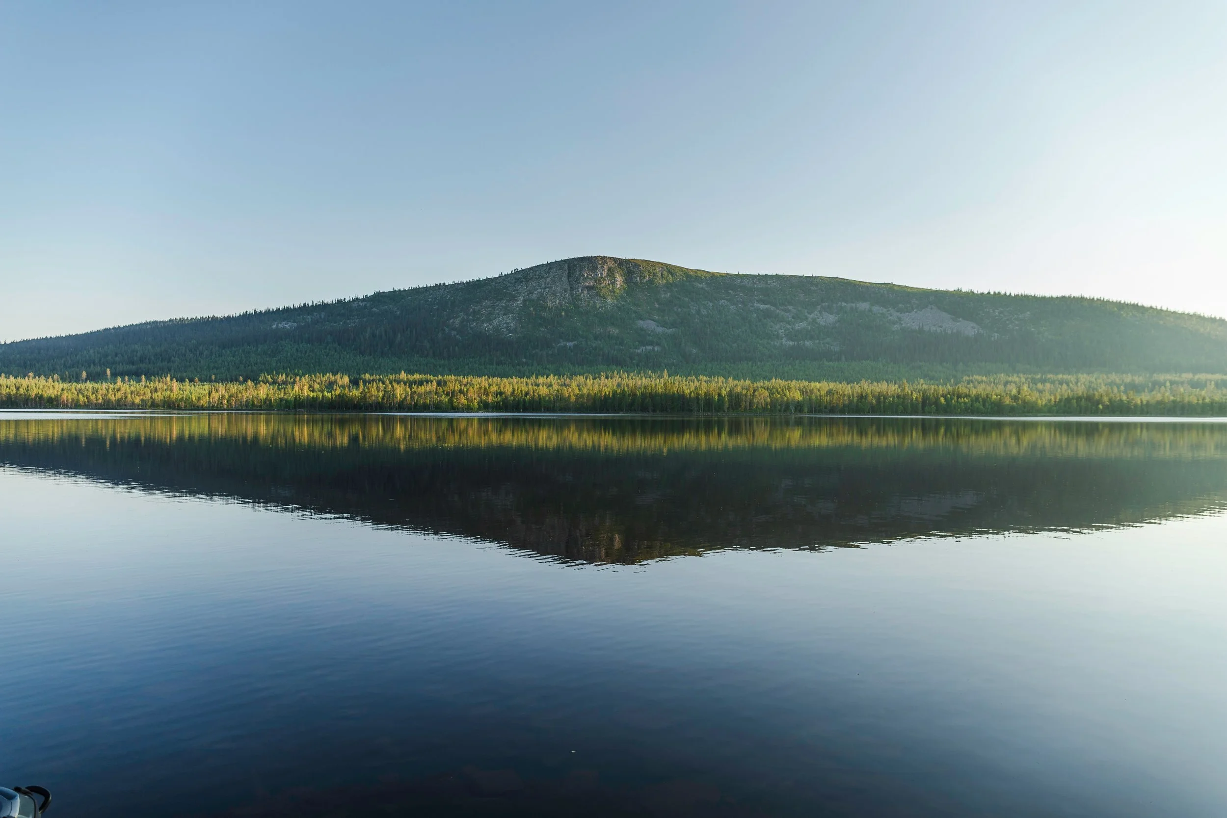 Lago tranquilo em Arvidsjaur, na Suécia, com uma montanha refletida na água ao início da manhã.