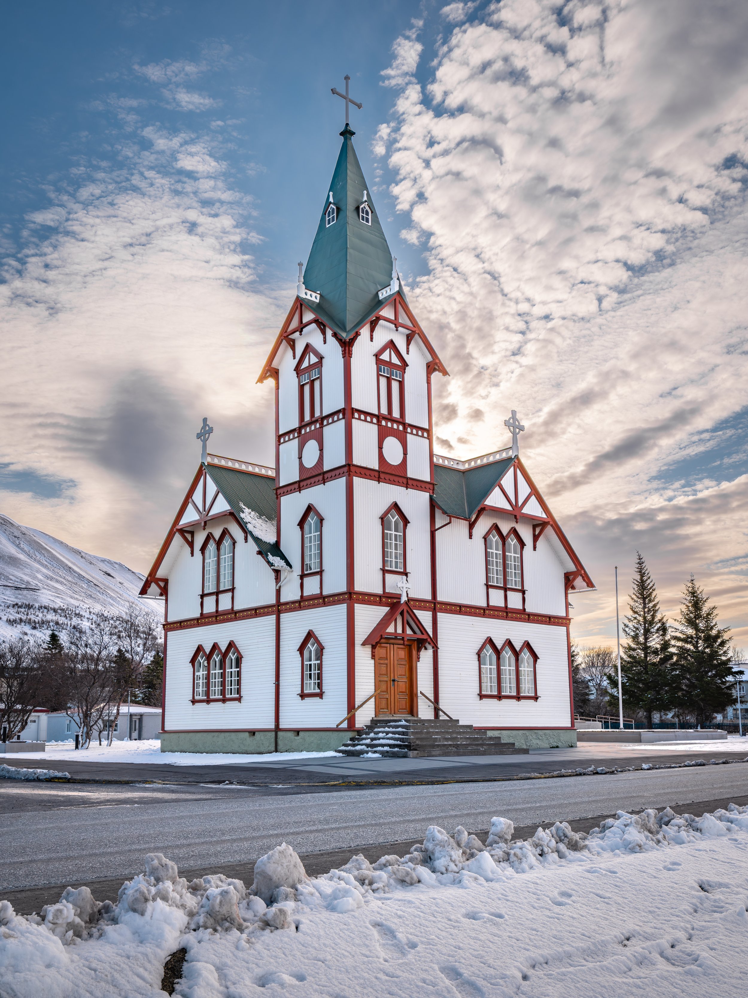 Igreja de Húsavík, de madeira branca e vermelha, rodeada por neve no norte da Islândia.