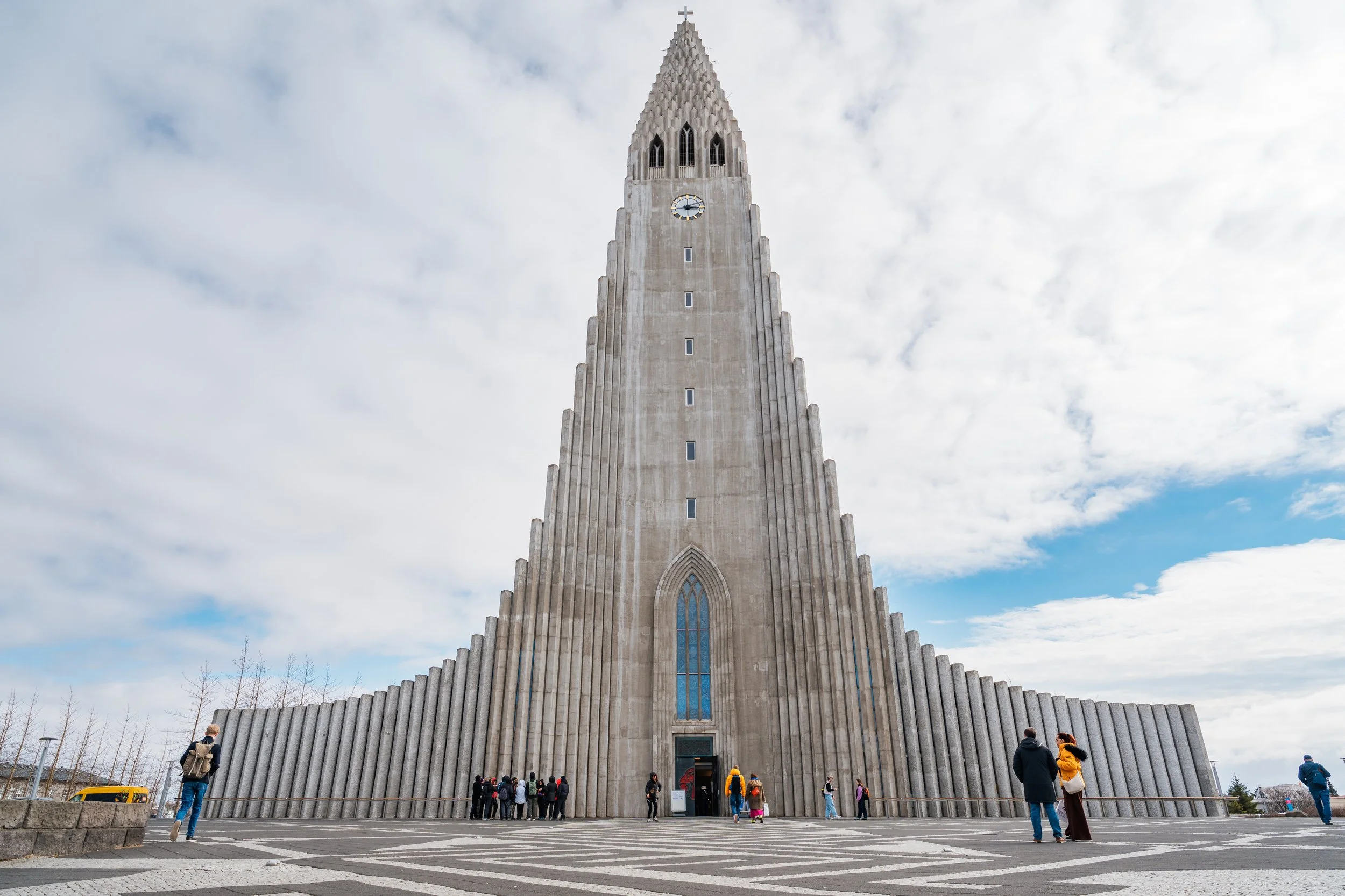 Hallgrímskirkja em Reykjavík, Islândia, vista de frente sob um céu parcialmente nublado.