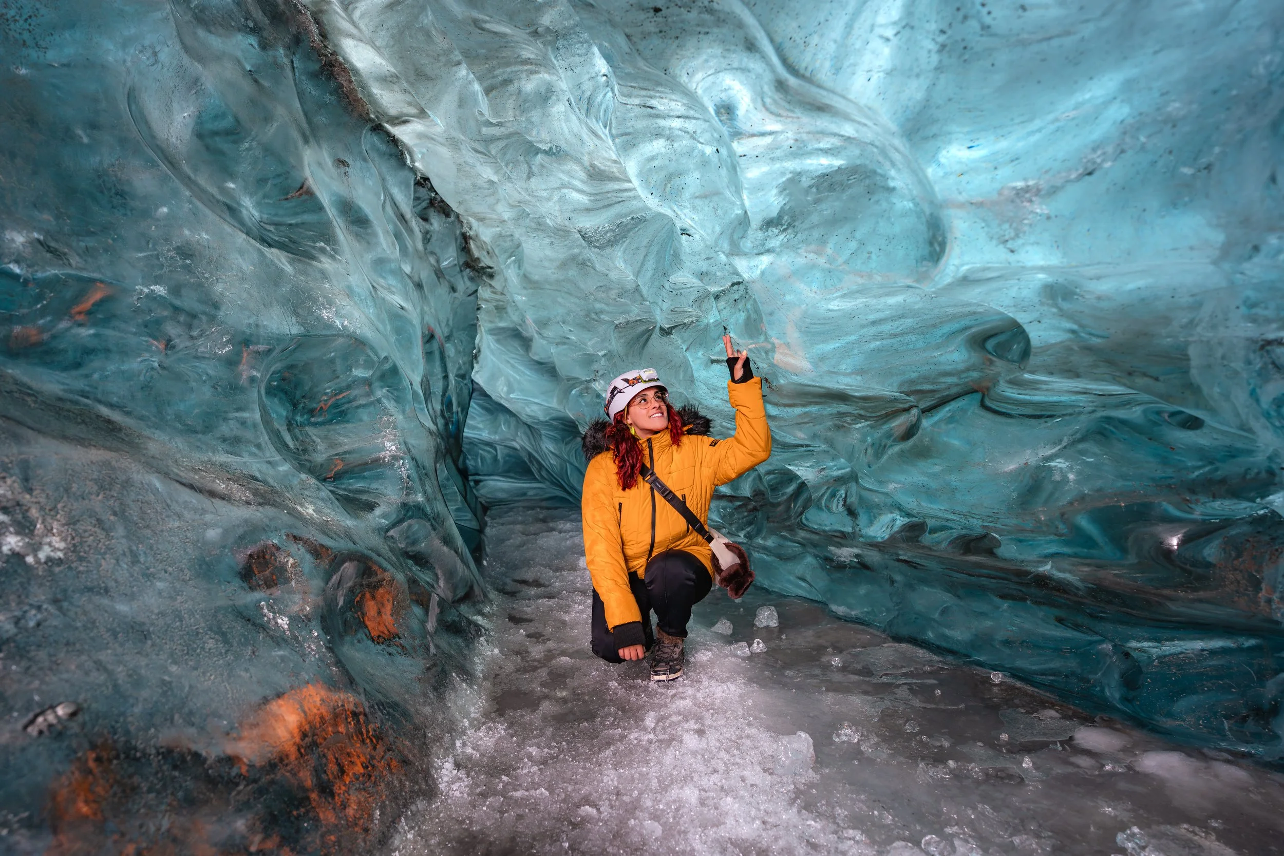 Viajante a explorar o interior de uma caverna de gelo azul na Islândia.