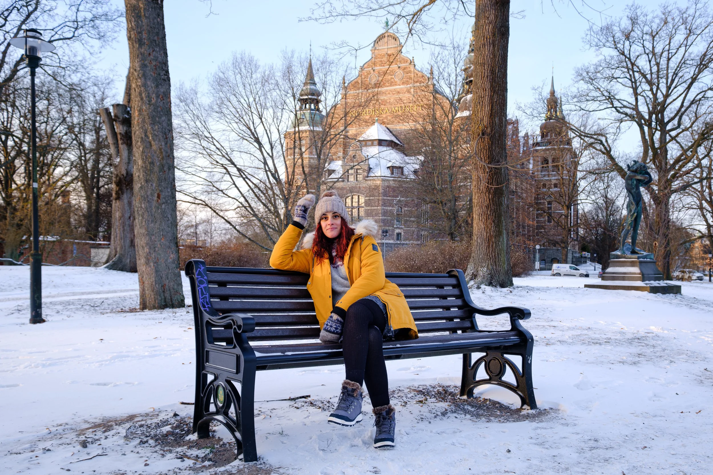 Viajante sentada num banco em Estocolmo no inverno, com o Nordiska Museet ao fundo.