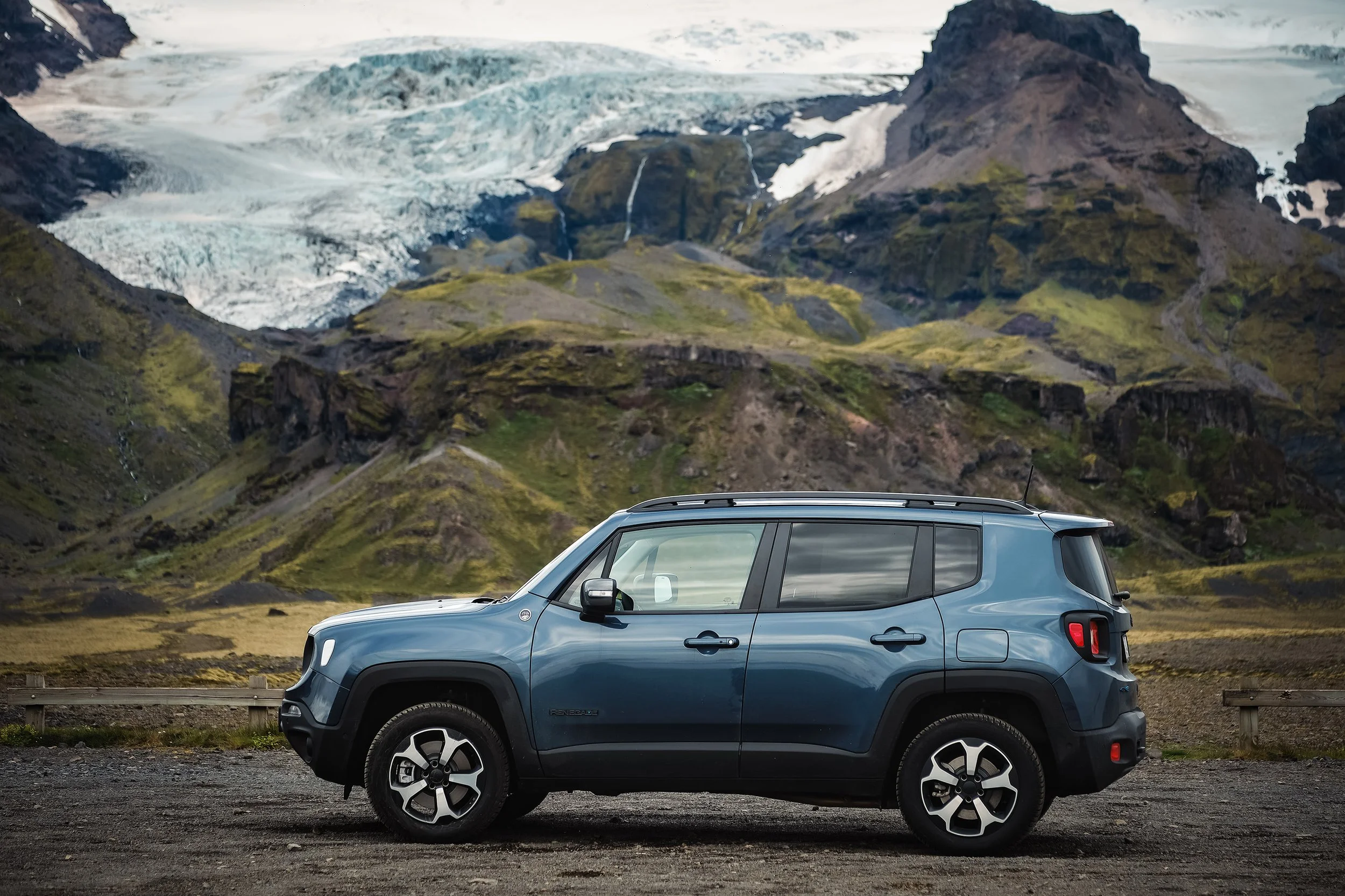 Carro 4x4 estacionado diante de um glaciar e montanhas cobertas de musgo na Islândia.