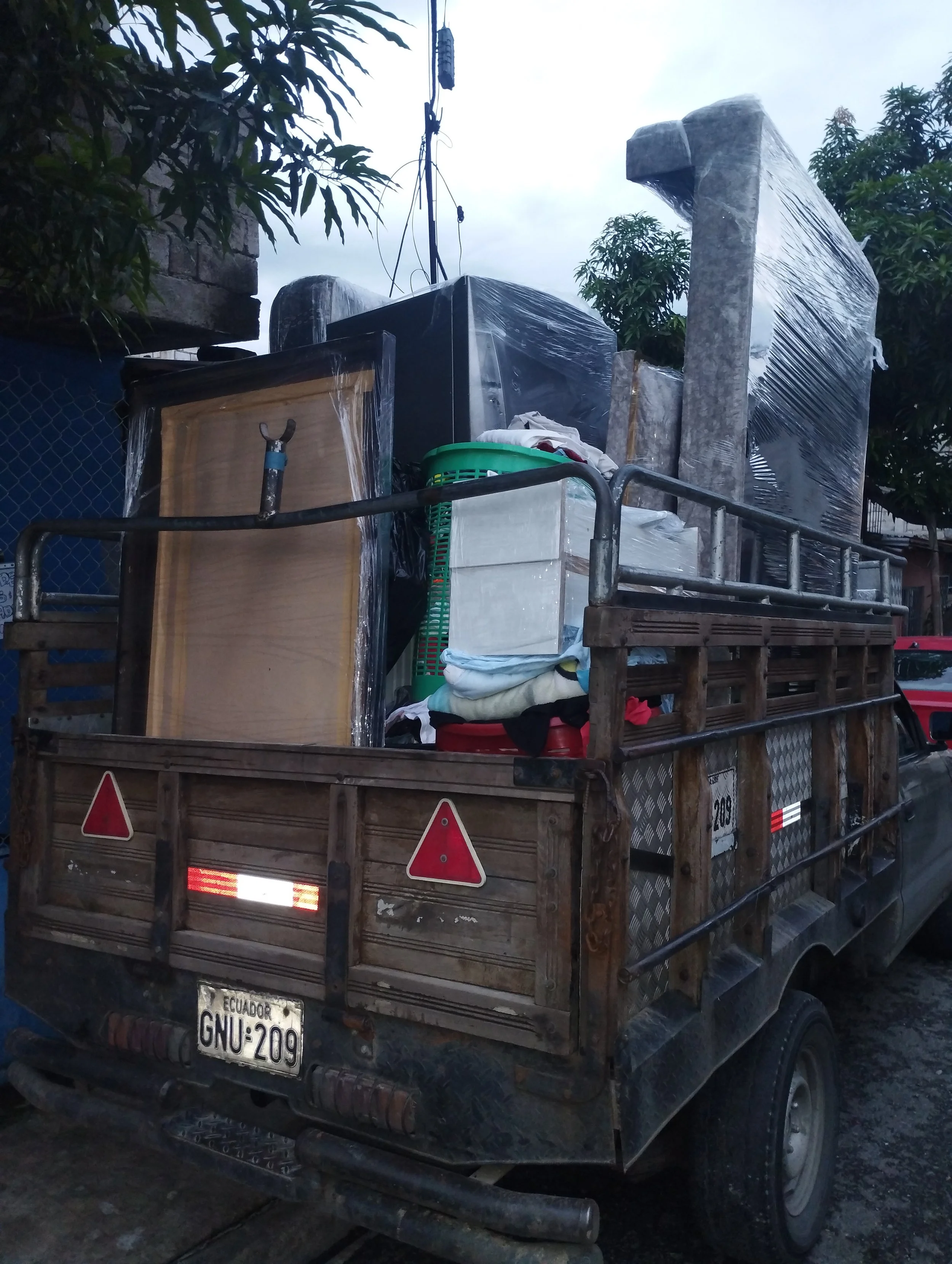 Camión de carga con objetos envueltos en plástico, incluyendo muebles y otros artículos, en una calle