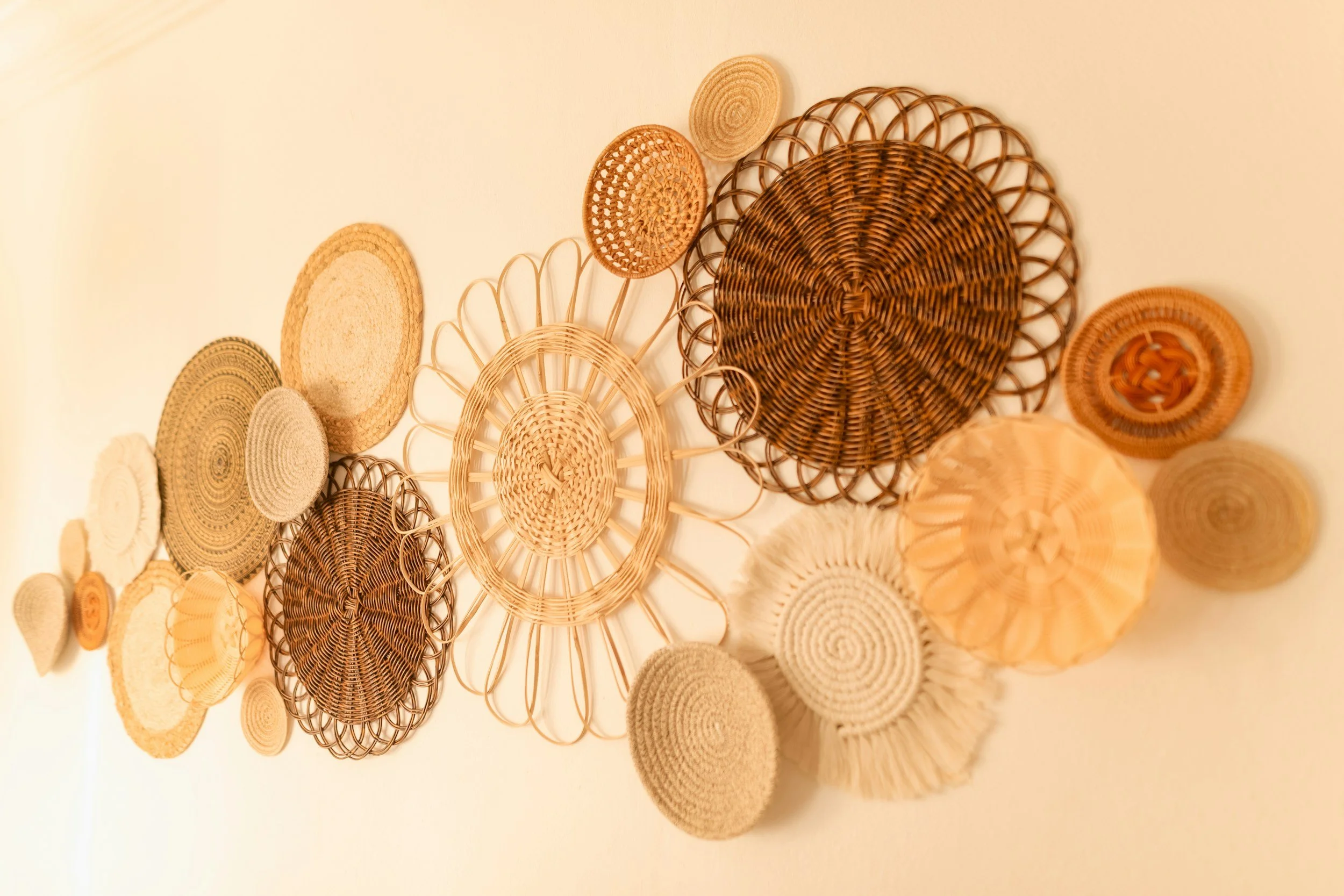 Wall decorated with multiple woven baskets in various shapes, sizes, and shades of natural wicker.