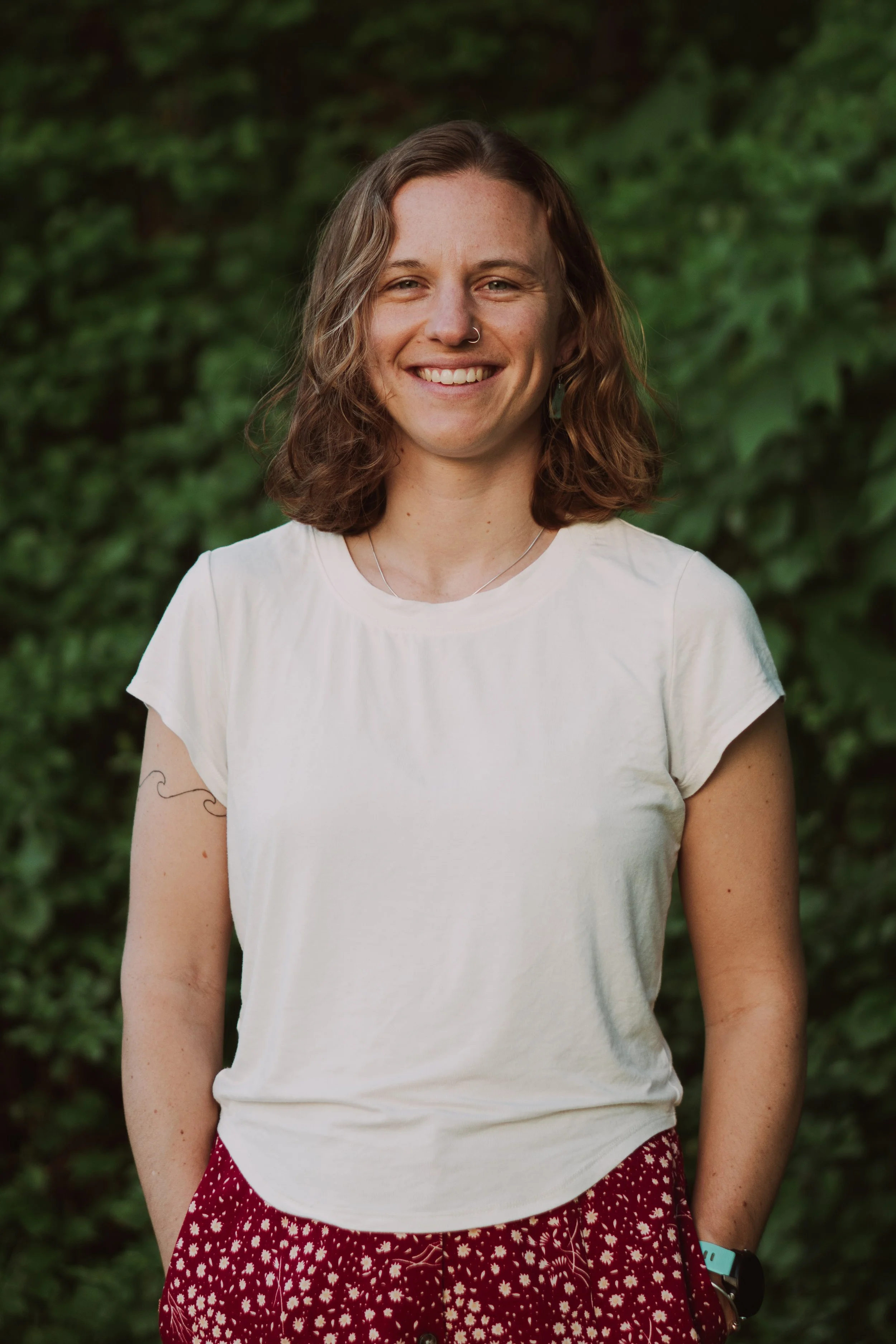 Woman smiling with trees in the background.