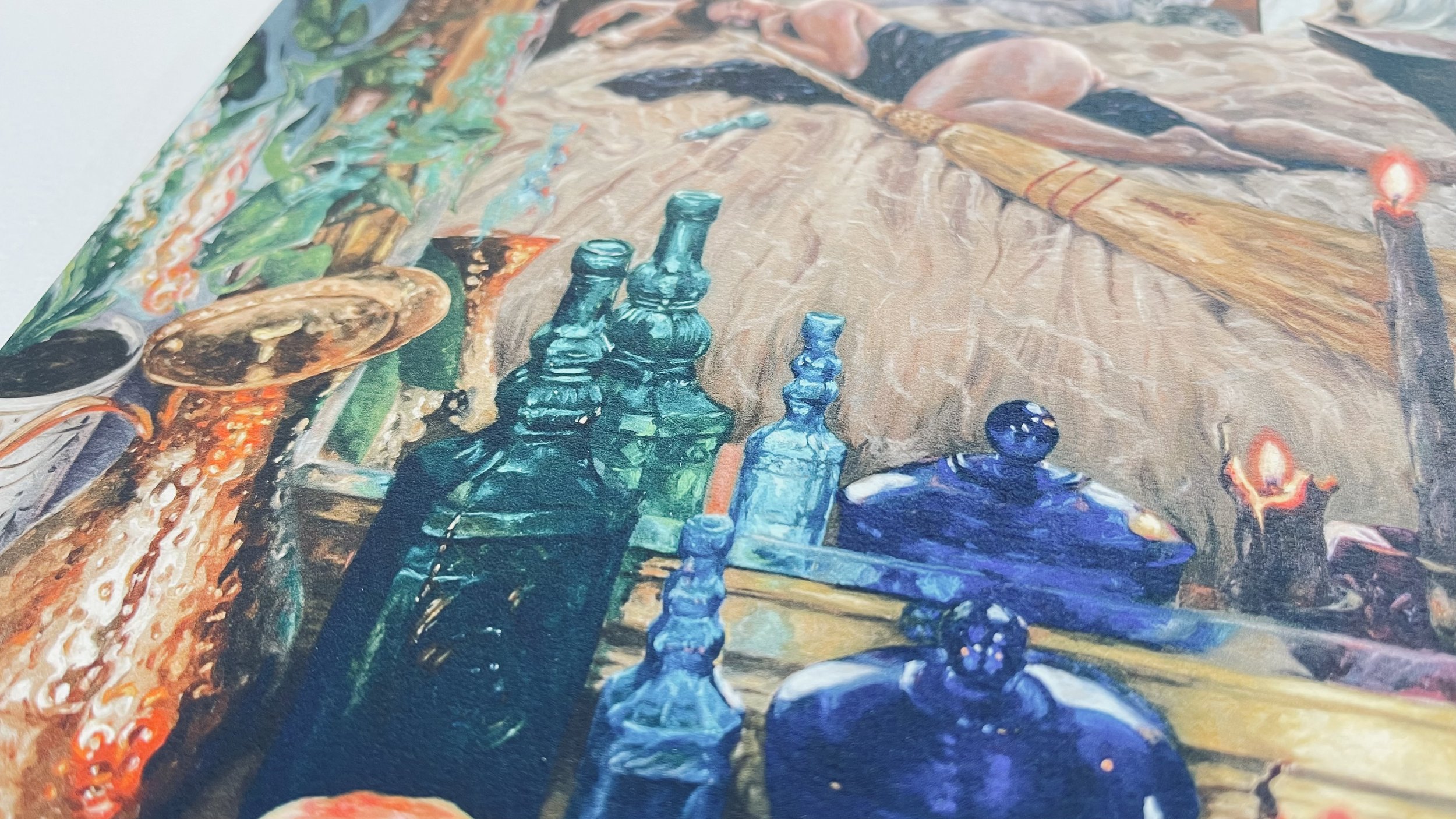 Close-up of a fine art print on somerset velvet textured cotton rag paper. The artwork is a colorful painting featuring glass bottles, a copper ewer, candles, and the reflection of a woman in the mirror laying with a broom.