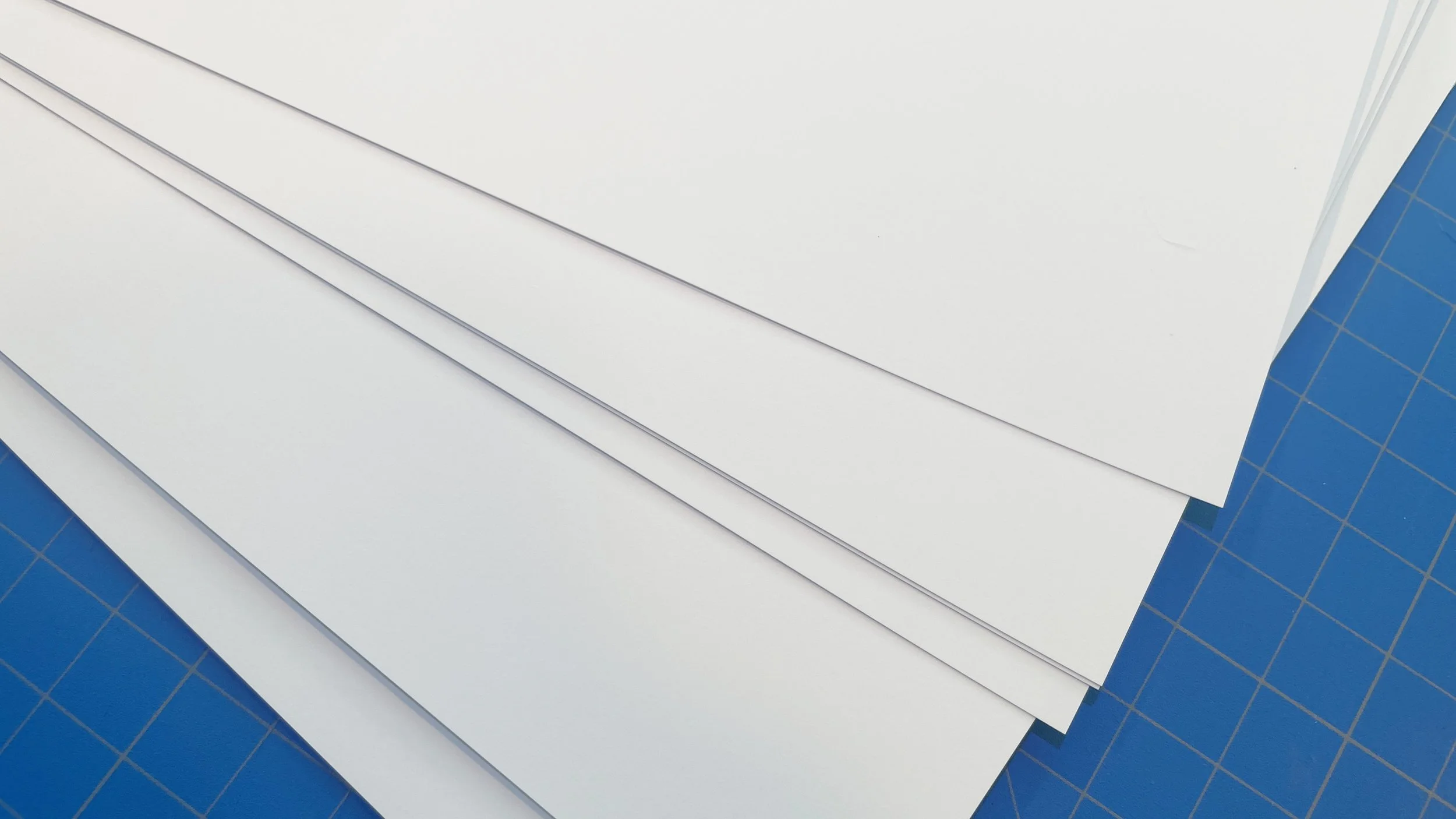 Close-up photo depicting a stack of super smooth, bright white, premium matte paper. Red River Polar Matte 230 gsm.