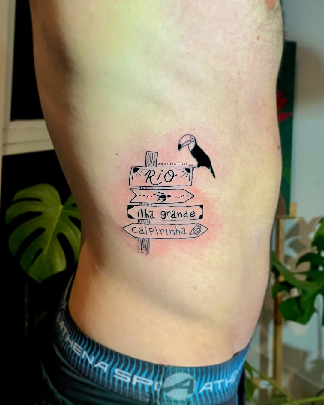 Tattoo de sinalização com uma gaivota, contendo a frase 'Rio ilha grande caipirinha'.