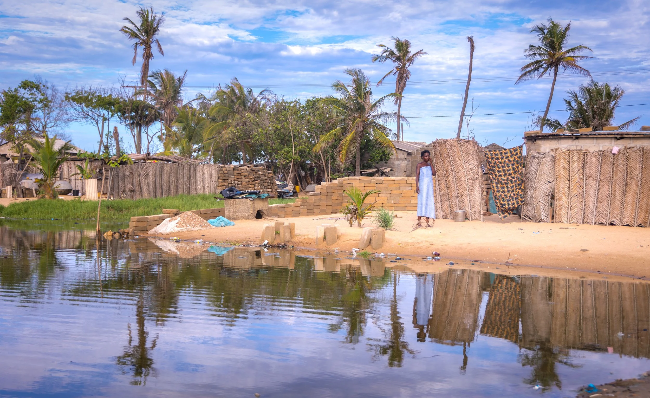 A woman stands outside her home in Agavedzi, Ghana. The town has experienced flooding from the ocean that has engulfed houses.