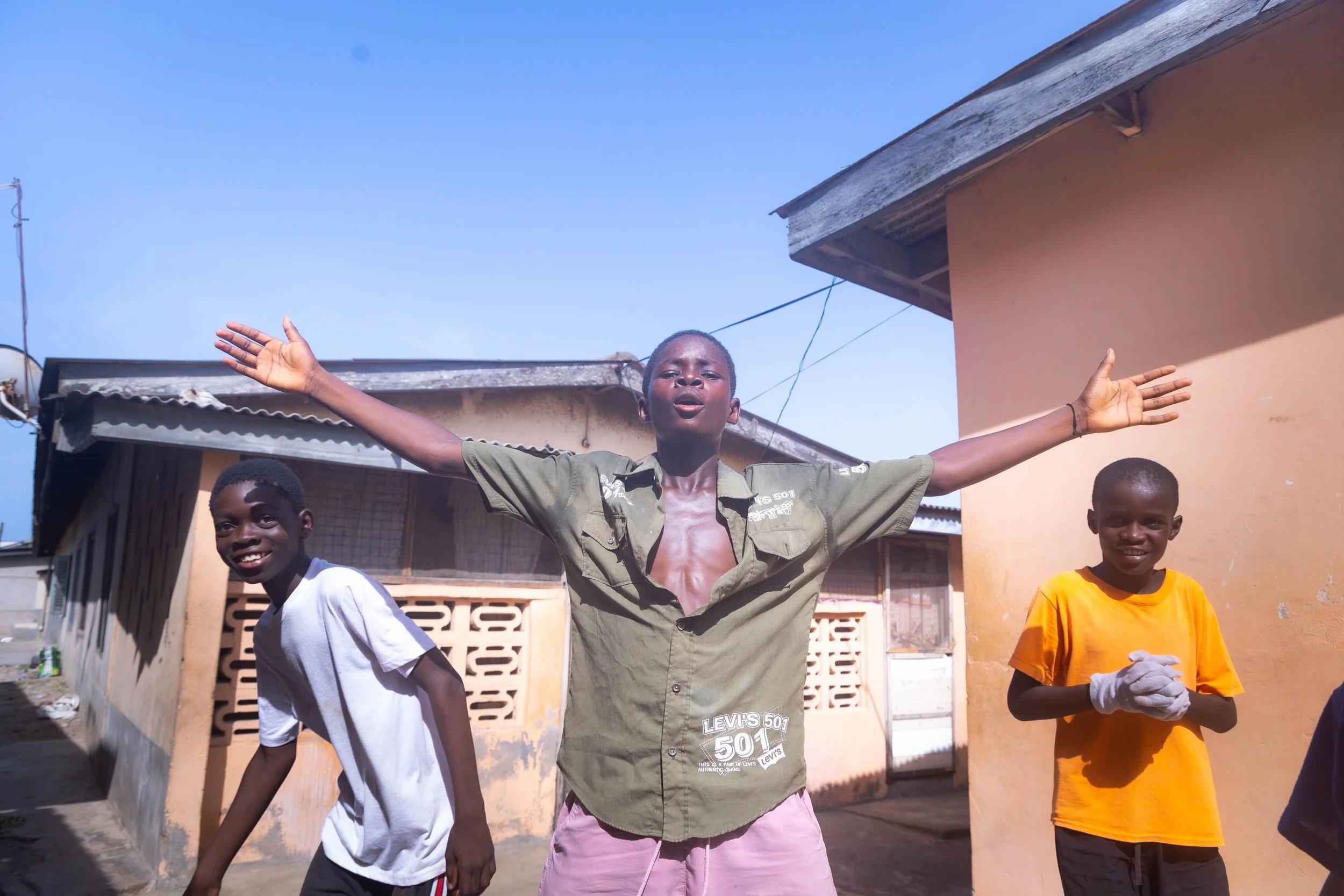 Three boys playing soccer in the alleyways of Teshie, Ghana with a little celebration.