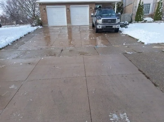 Concrete driveway with a parked pickup truck and snow on the sides.