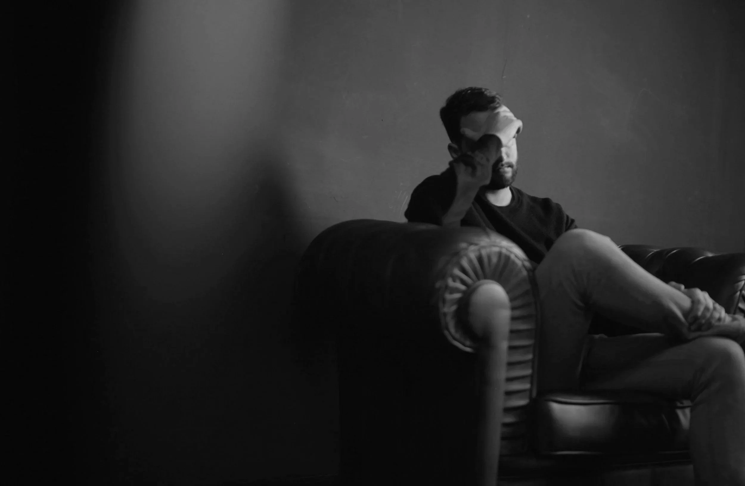 A man resting his head in his hand while sitting on a couch