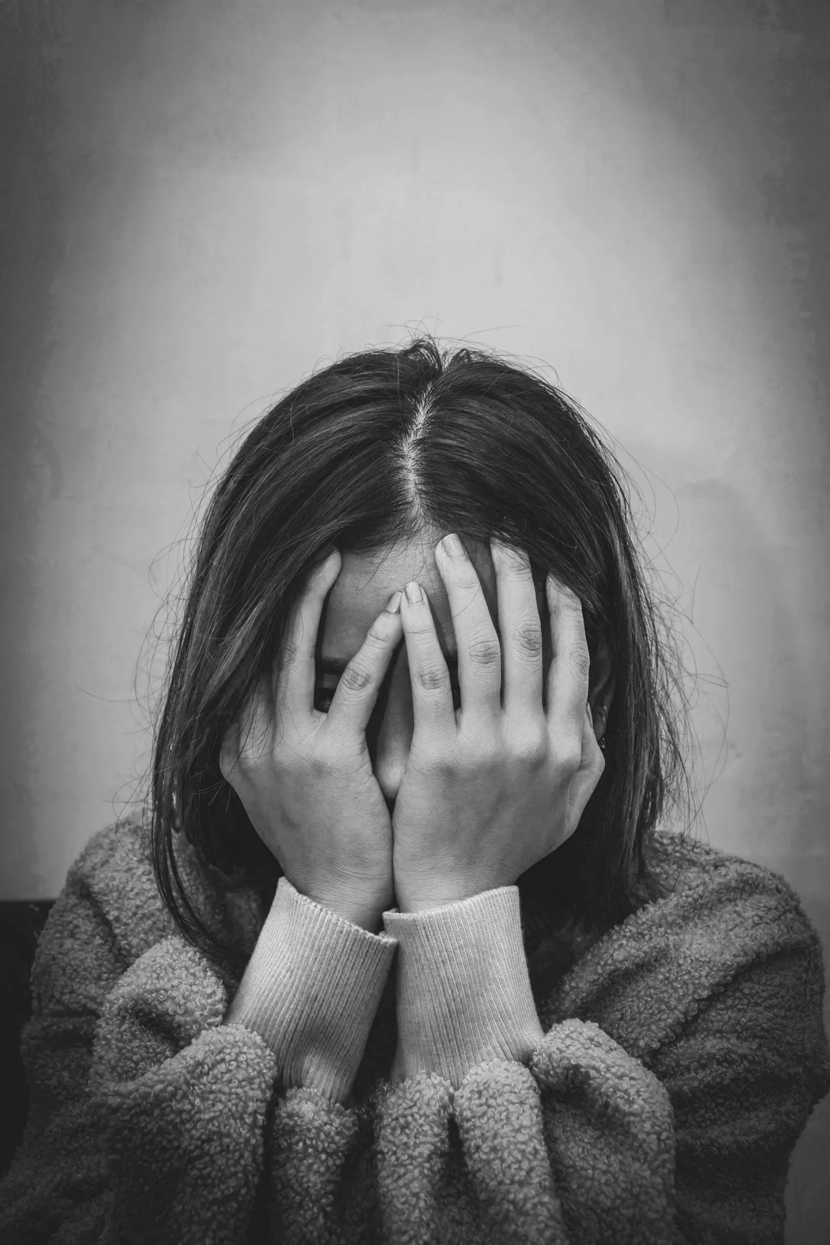 A woman with her hands over her face in distress or unease.