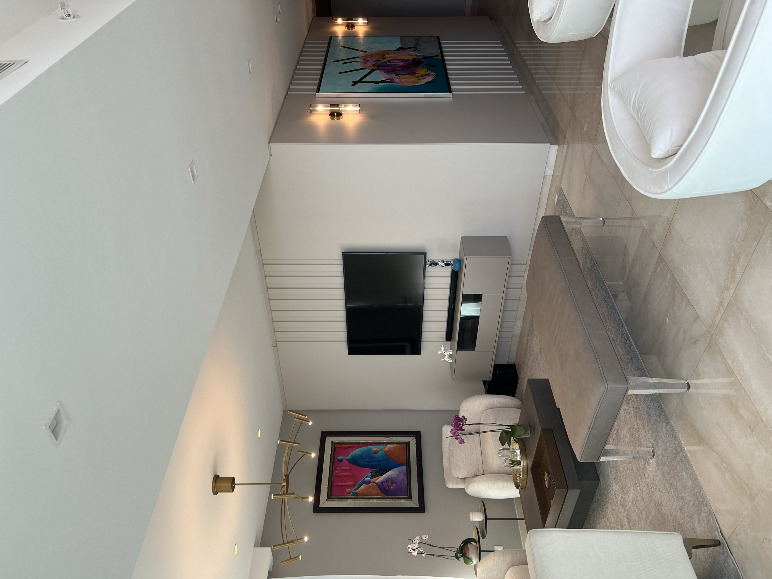 Sala de estar moderna con sillón, mesa de café, televisor en pared y decoraciones florales.