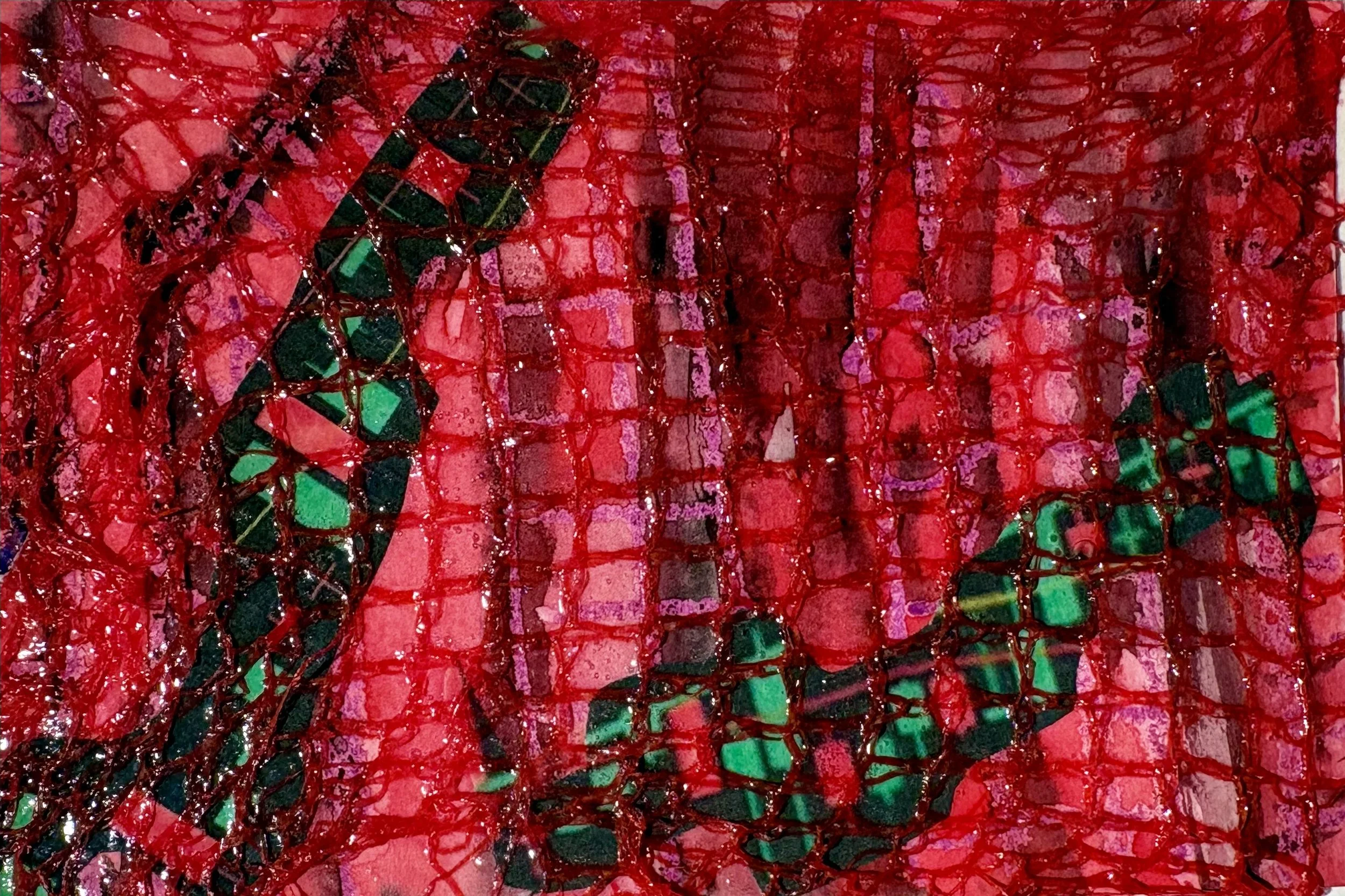 Close-up of a mosaic-like artwork with red, green, pink, and black pieces, and a red net overlay. Two strains of candles occupied the space and atmosphere.