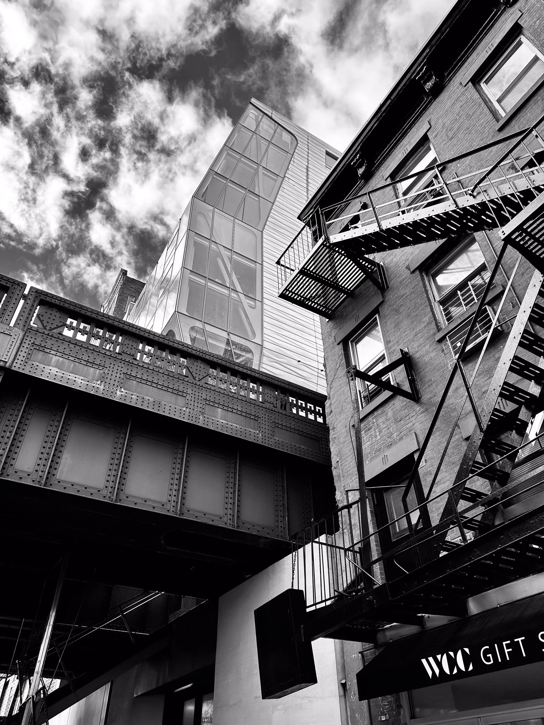 Contrast between the High Line and facades of an old tenement building with iconic fire escape and a new condominium, New York City. Architectural art photography.