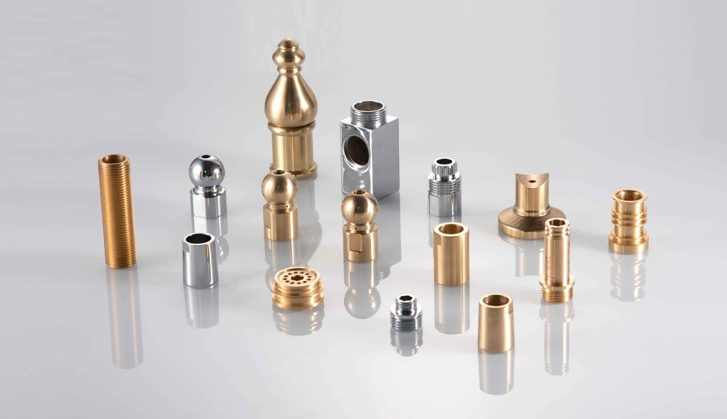 Collection of various metal mechanical parts in gold and silver colors on a reflective surface.