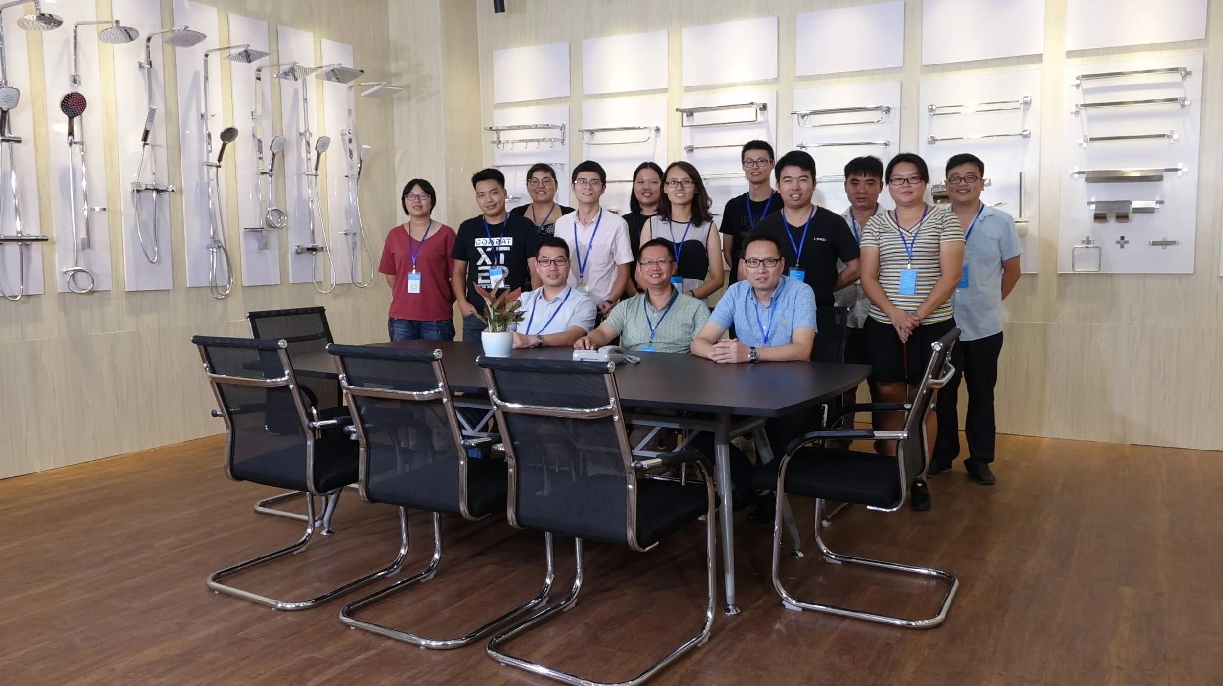 Group of people in a conference room with medical shower equipment displays on the wall behind them.