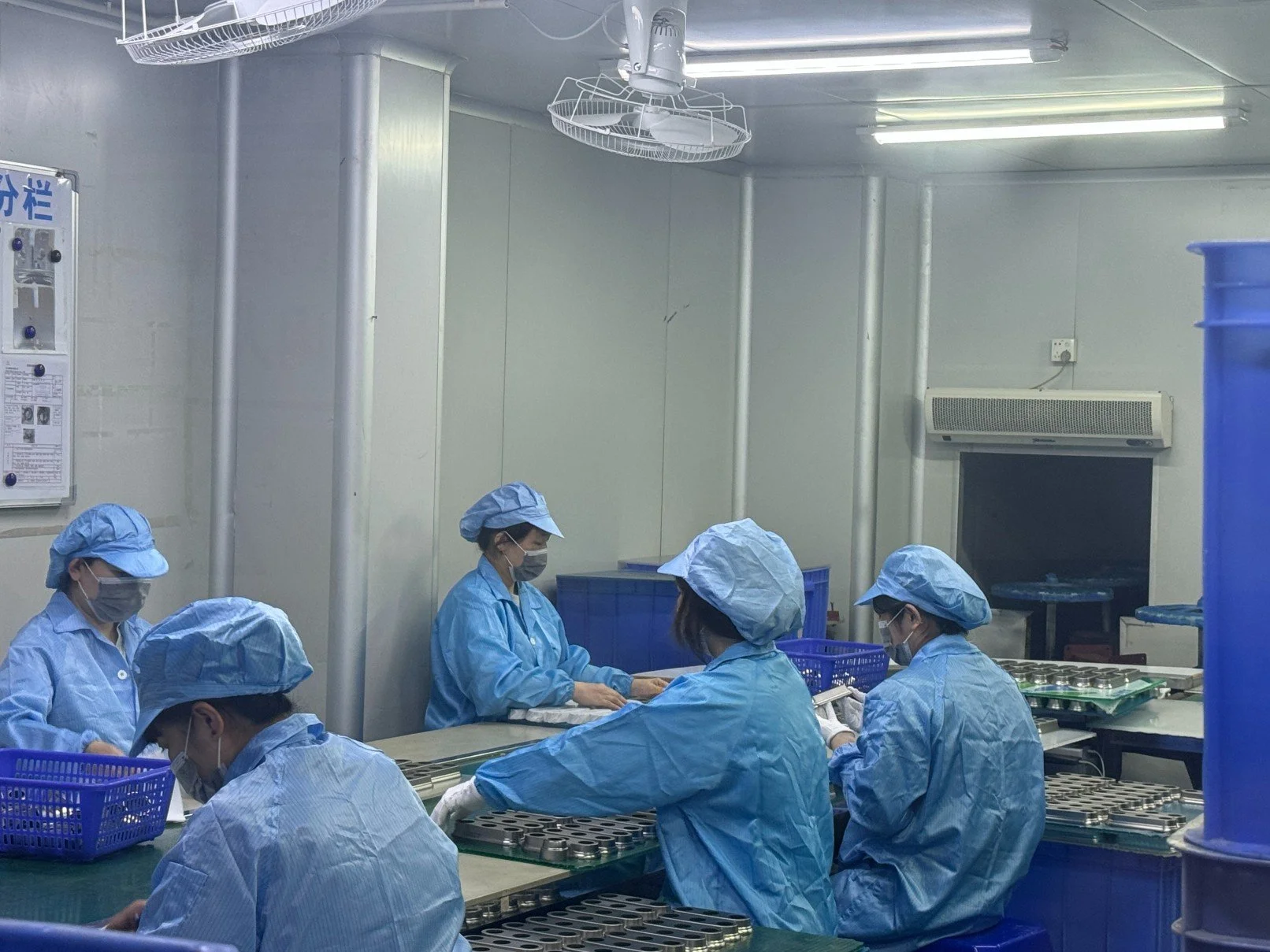 Standard clearn room Workers in blue protective gowns, masks, and hair covers working at assembly line in a factory or laboratory.