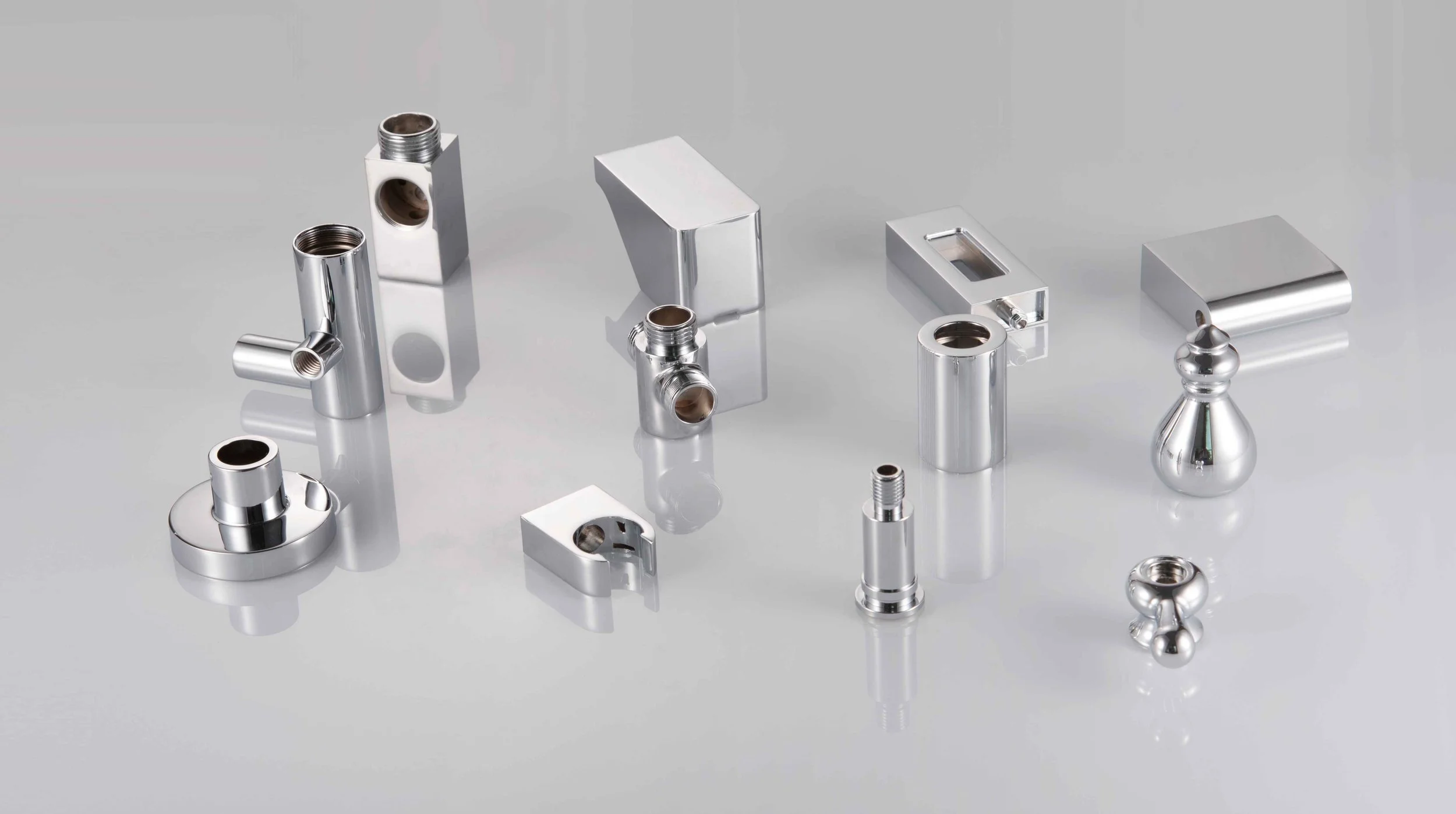 Various small metallic machined components on a light gray surface.