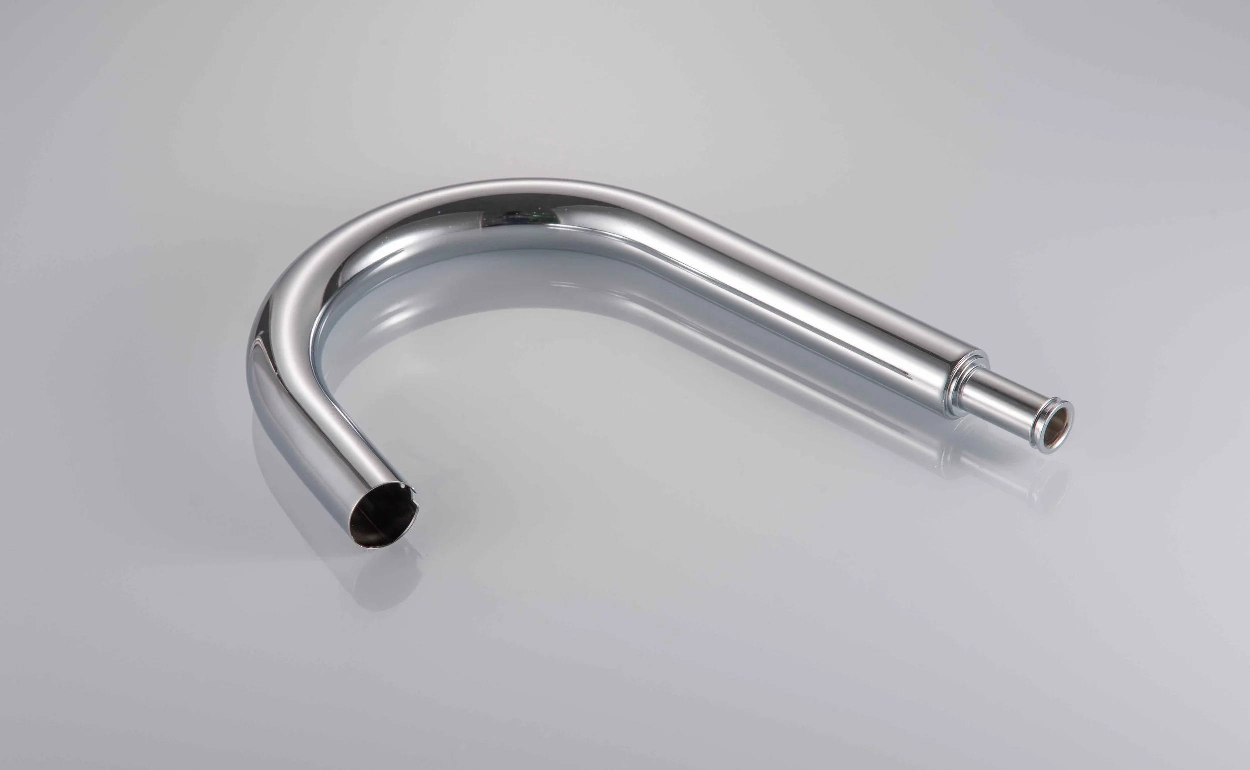 A shiny, metallic, U-shaped pipe with a smaller diameter extension on one end, lying on a reflective surface.