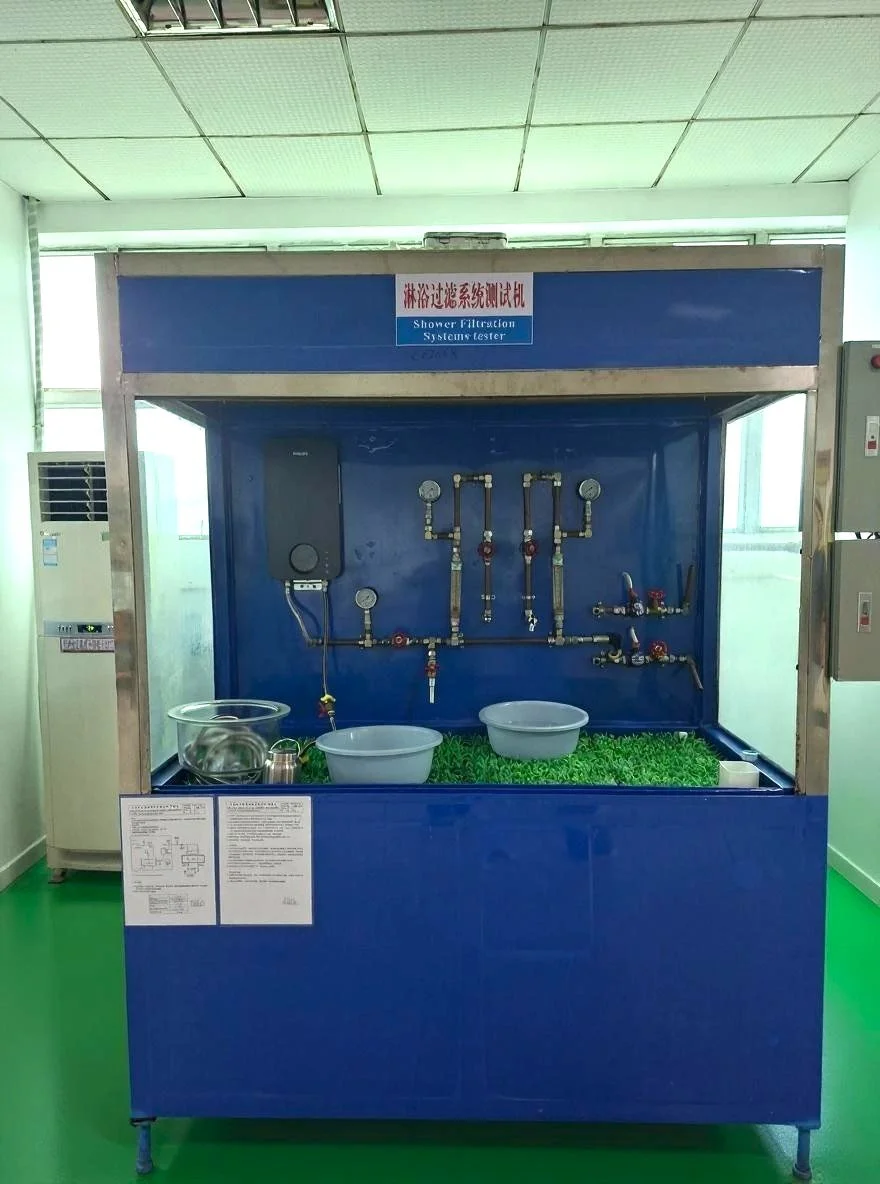 A shower filtration system tester with pipes, gauges, and bowls, set on a blue background with green artificial grass at the bottom, in a room with green flooring and a window.