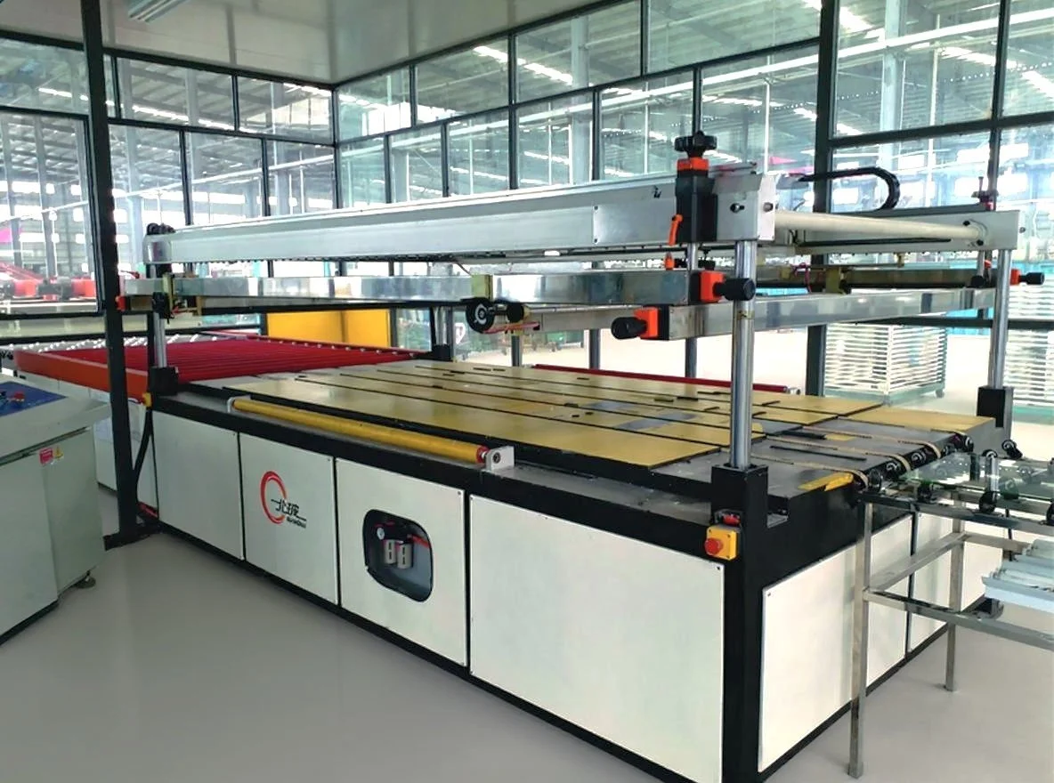 Industrial conveyor belt system with yellow and red rollers inside a modern factory or warehouse, surrounded by large glass windows.