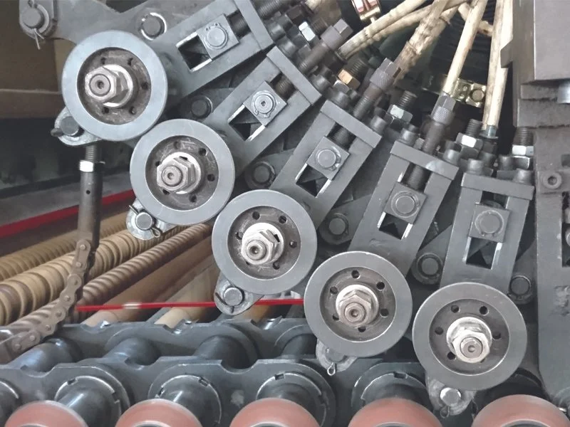 Close-up of industrial machinery with metal rollers, bolts, and mechanical components aligned in a complex arrangement.
