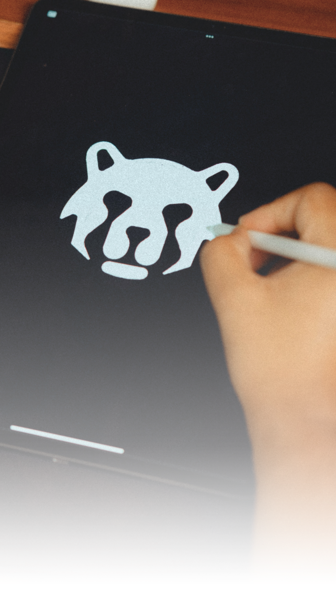 A person drawing the logo of a stylized animal face on a tablet with a white stylus pen.