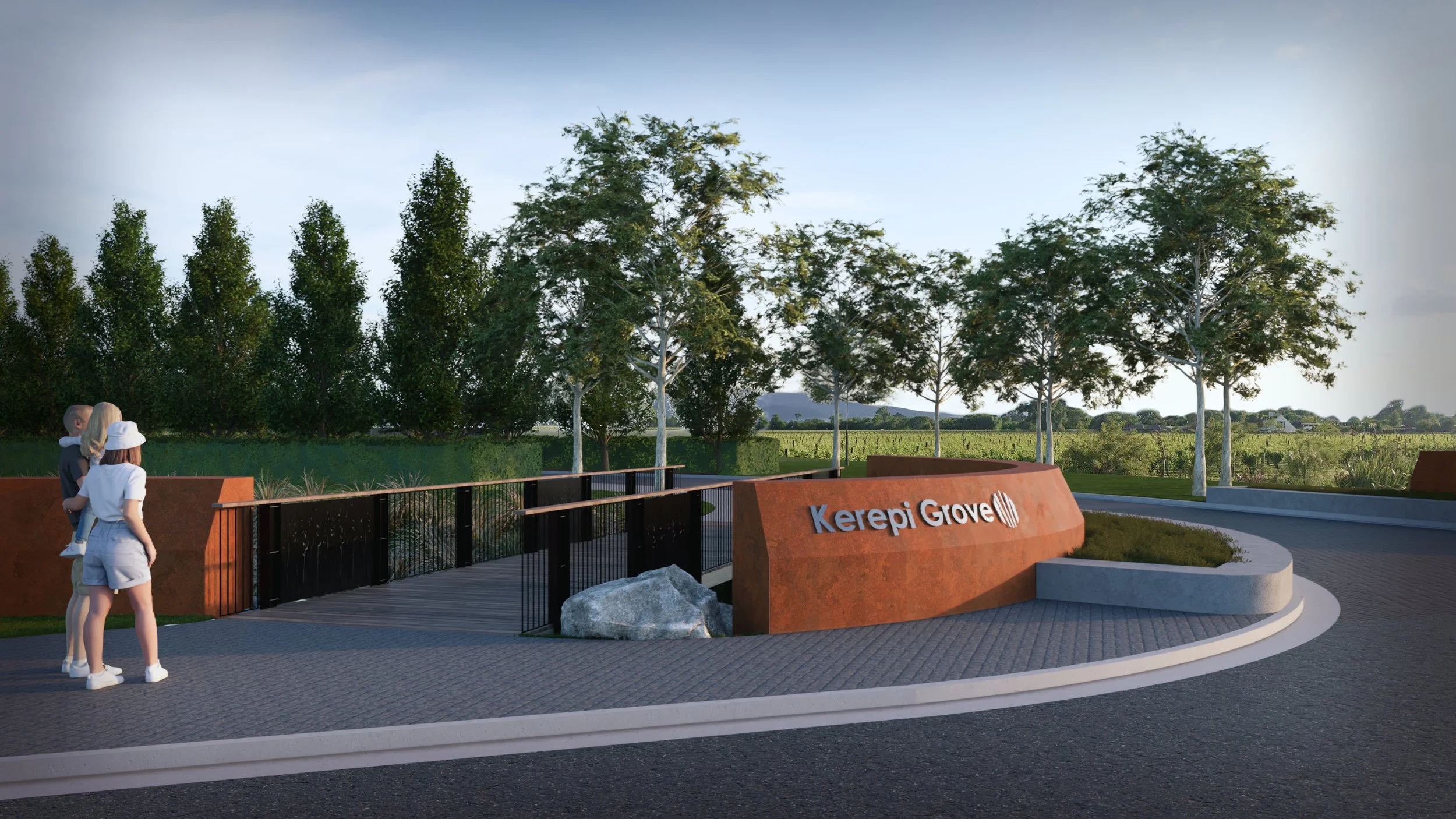 Two people standing near the entrance sign for Kerepi Grove, a curved stone sign with trees in the background and a clear sky.