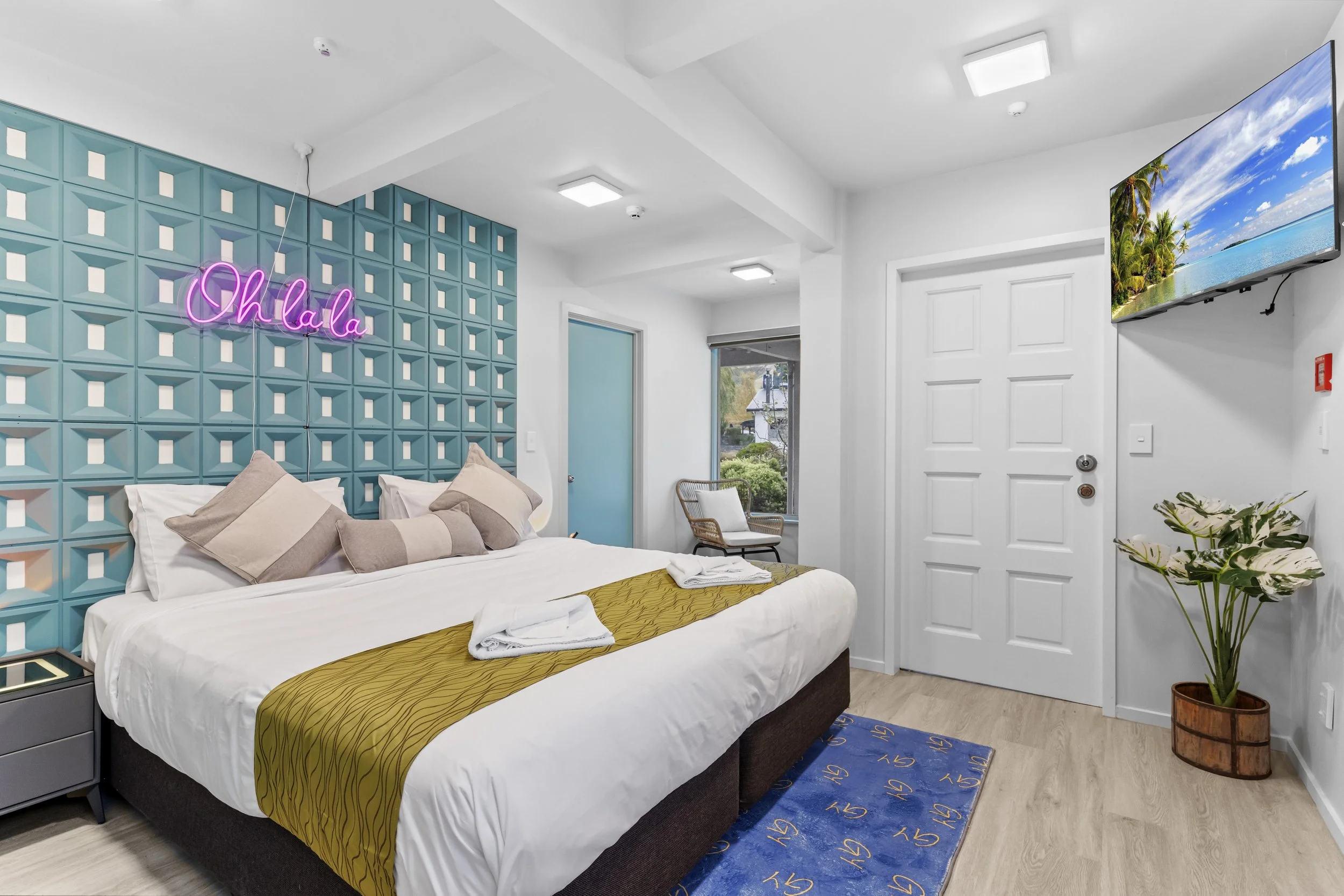 Hotel room with a bed, decorative pillows, a neon pink 