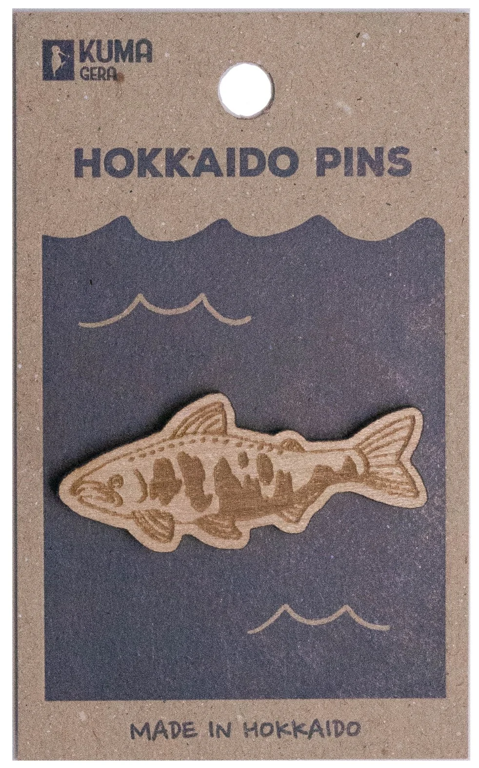 A cardboard package containing a pin shaped like a fish. The package is labeled "Hokkaido Pins" and indicates it is made in Hokkaido, Japan.