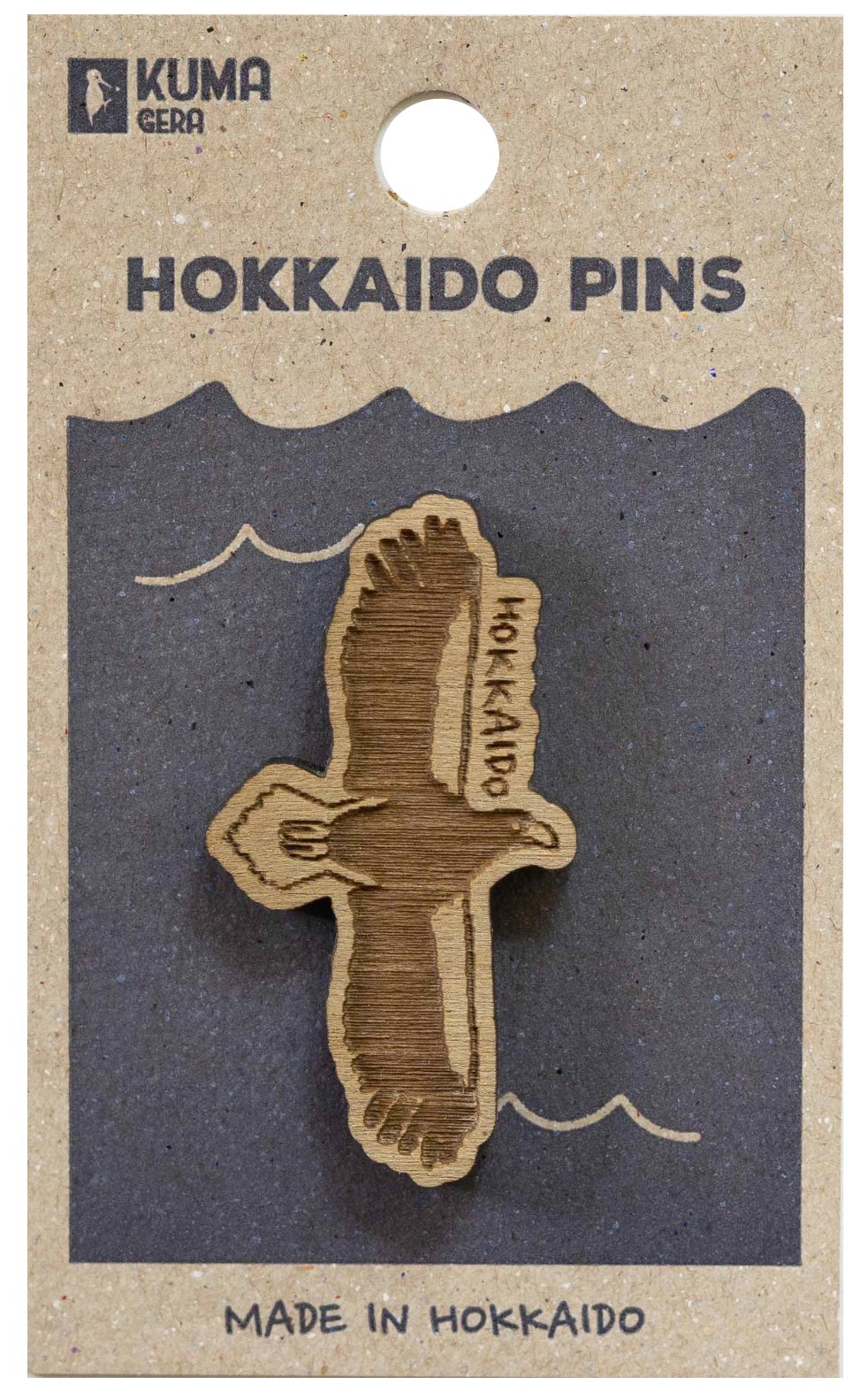 Hokkaido pins in the shape of the island of Hokkaido, made of wood, on black and beige packaging with text indicating they are made in Hokkaido.