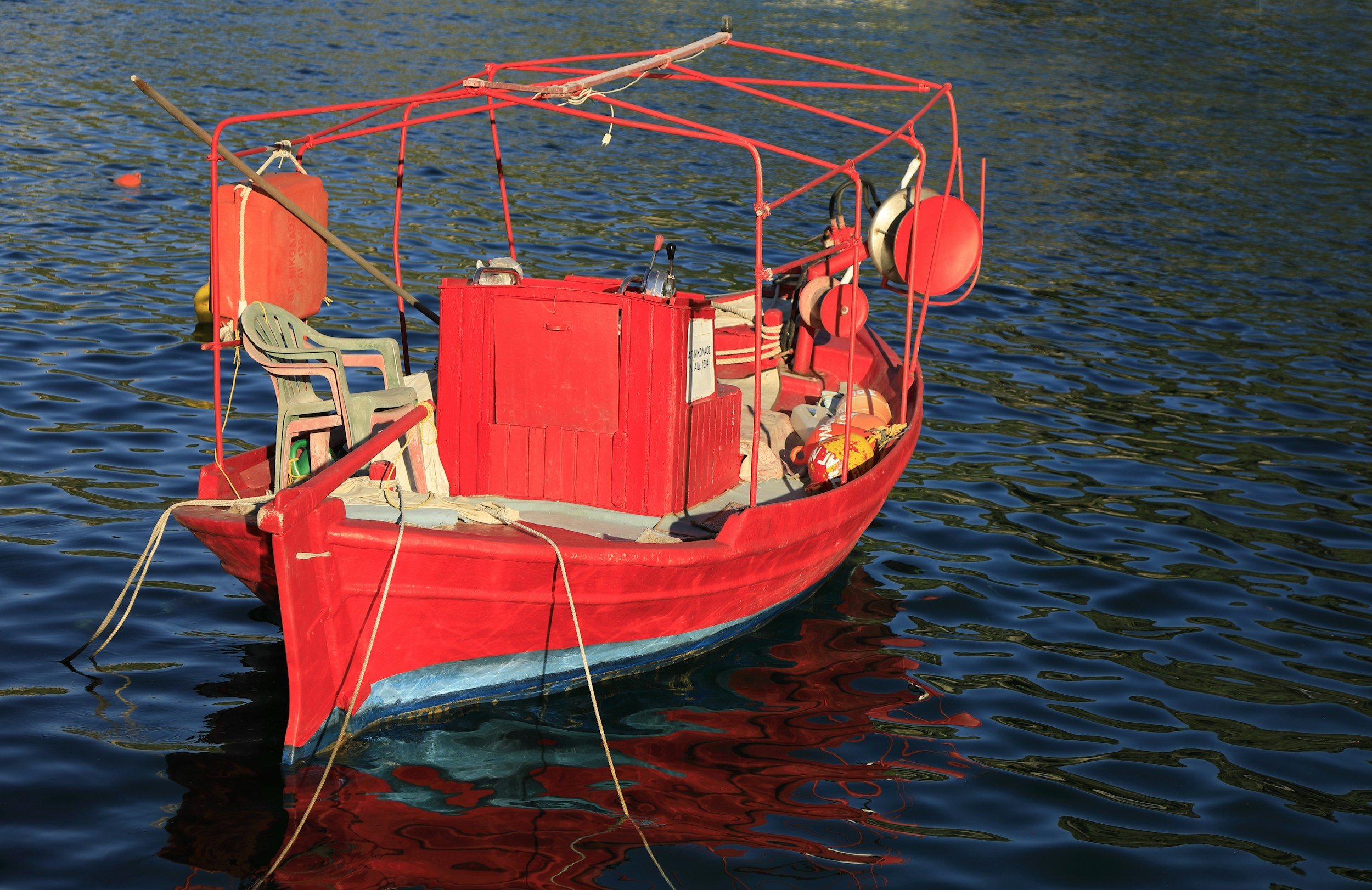 A red rescue boat with chairs, equipment, and life-saving gear, floating on calm water.