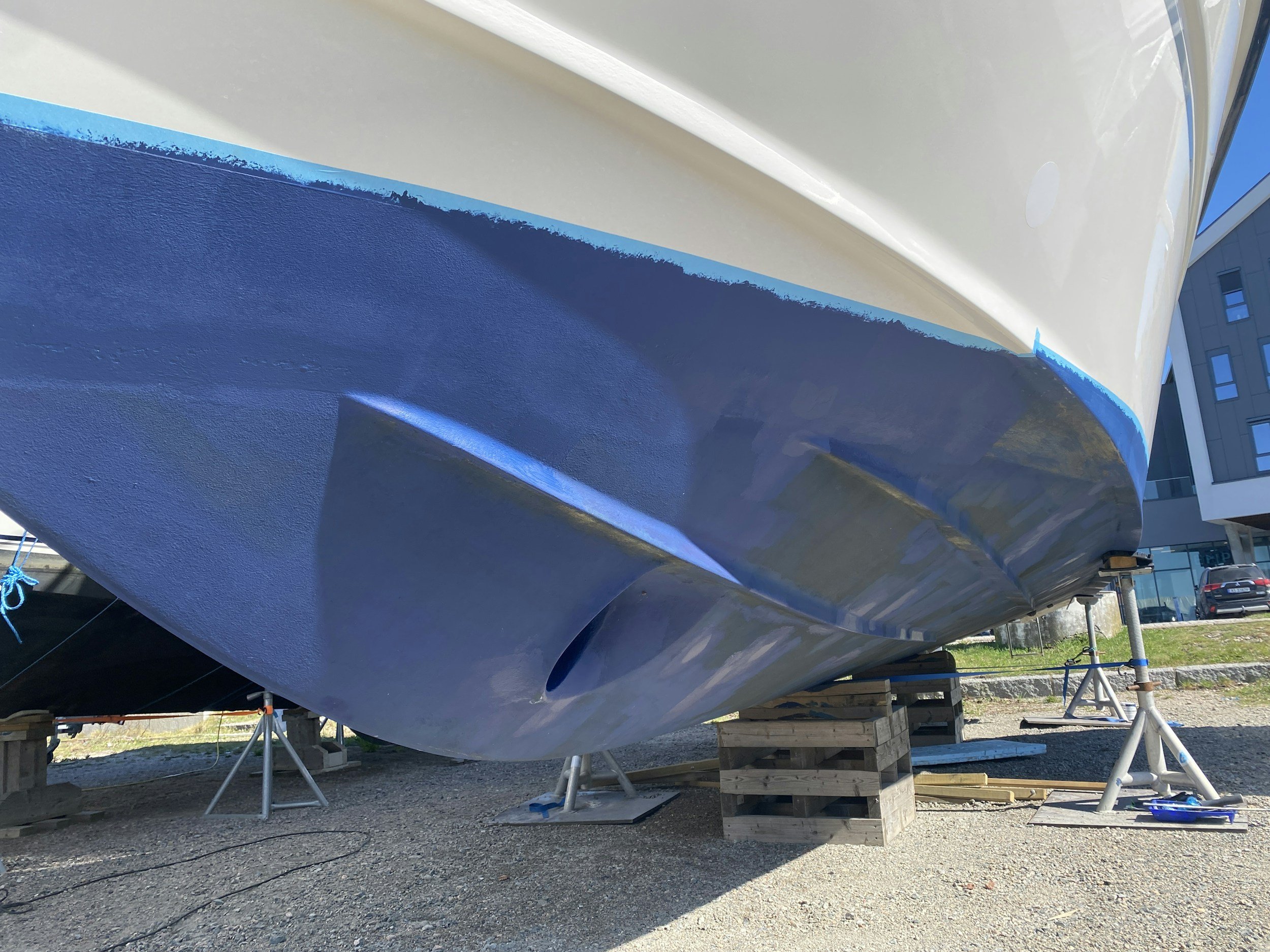 Close-up of the bottom of a boat on supports, showing the propeller and the hull painted in blue and white.