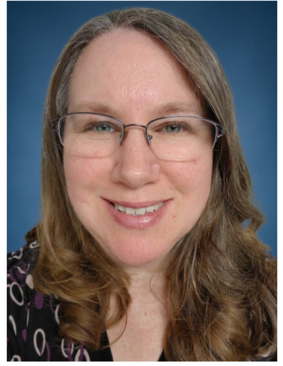 A woman with long brown hair, glasses, and a friendly smile, against a blue background.