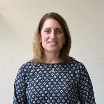female with mid length dark hair smiling at the camera