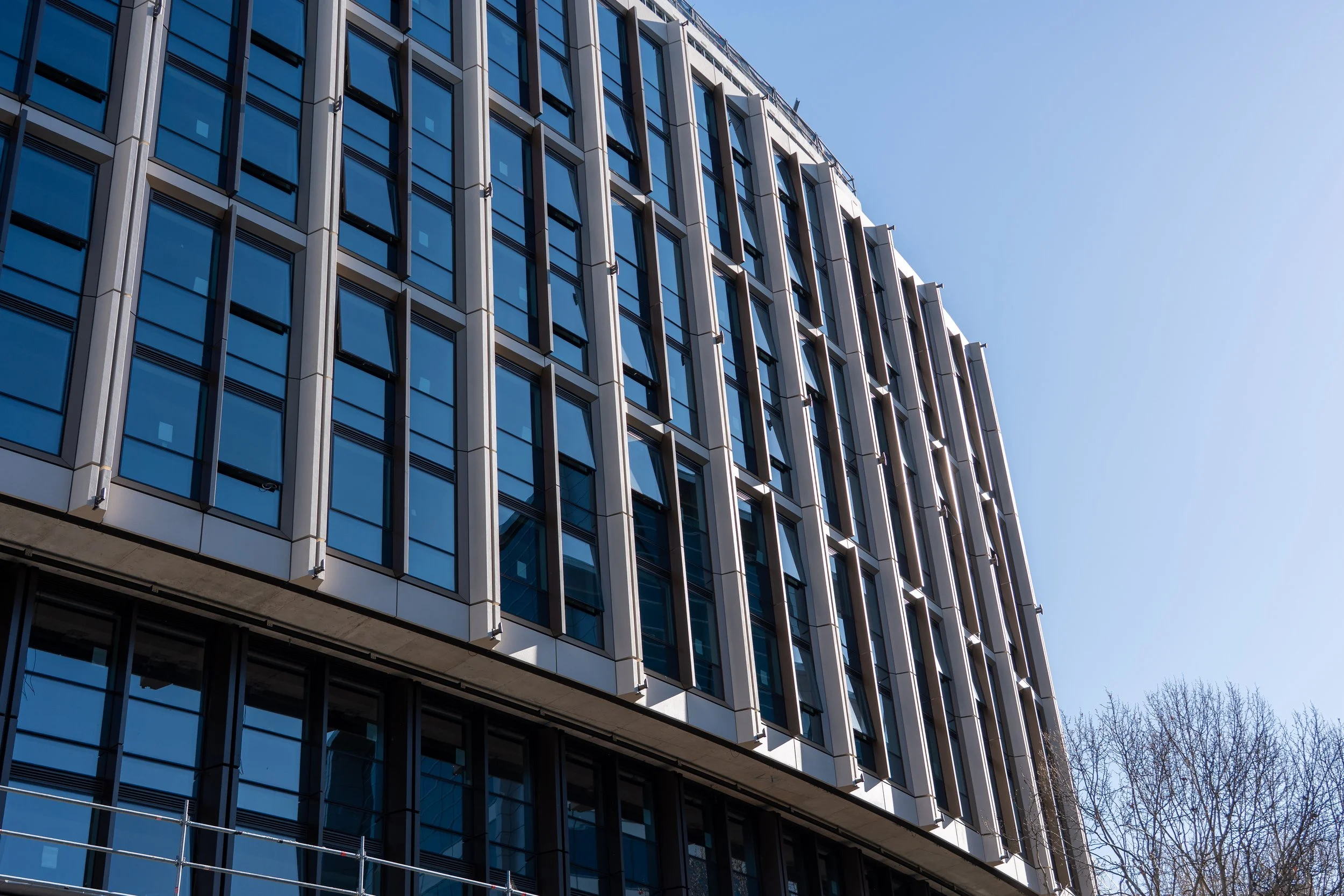 Modern multi-story building with glass windows set against a clear blue sky.