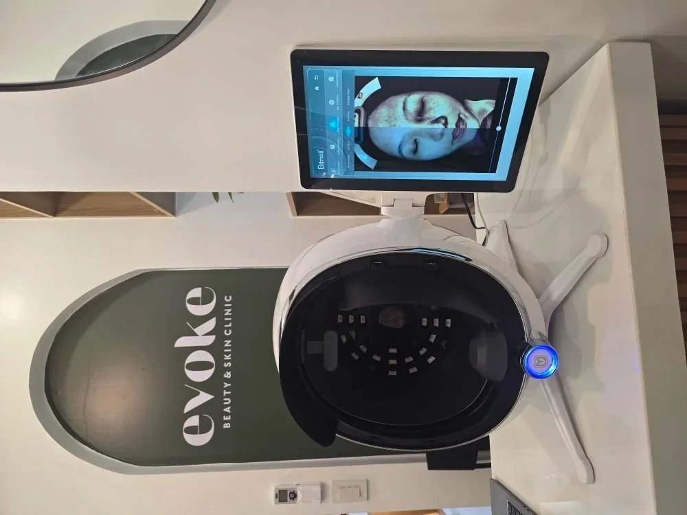 A futuristic skincare device connected to a tablet displaying a woman's face for a facial treatment at Eve Aesthetic & Skin Clinic.