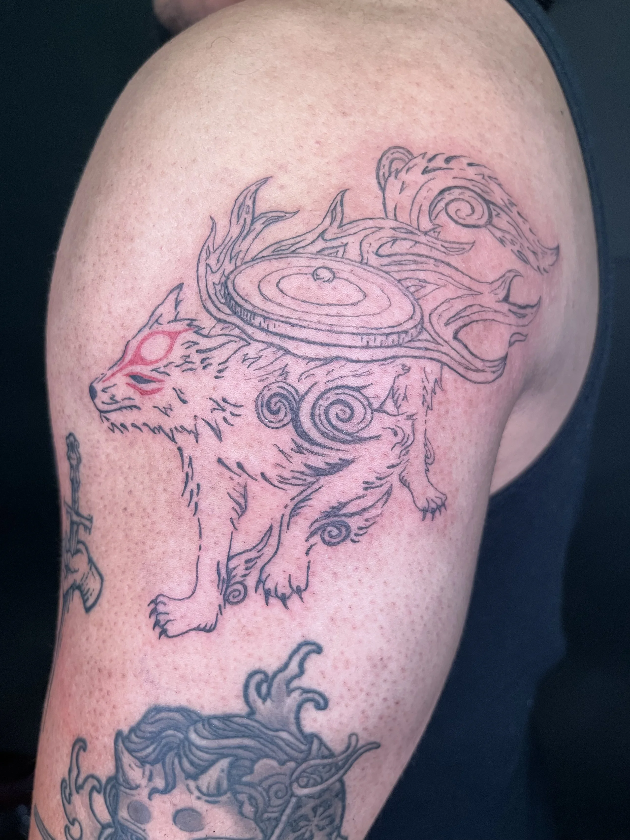 Outline tattoo of a wolf and swirling flame elements.