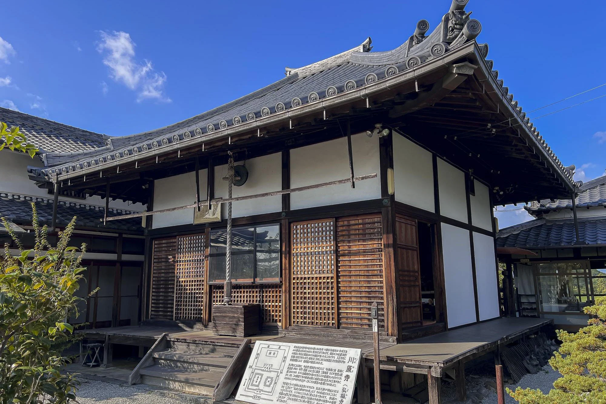 Traditional Japanese building with wooden structure and tiled roof under a clear blue sky.