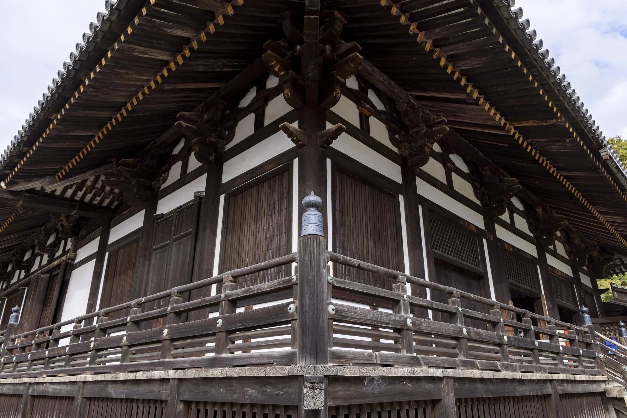 Traditional Japanese wooden building with a raised platform, dark wood panels, and a curved tiled roof.