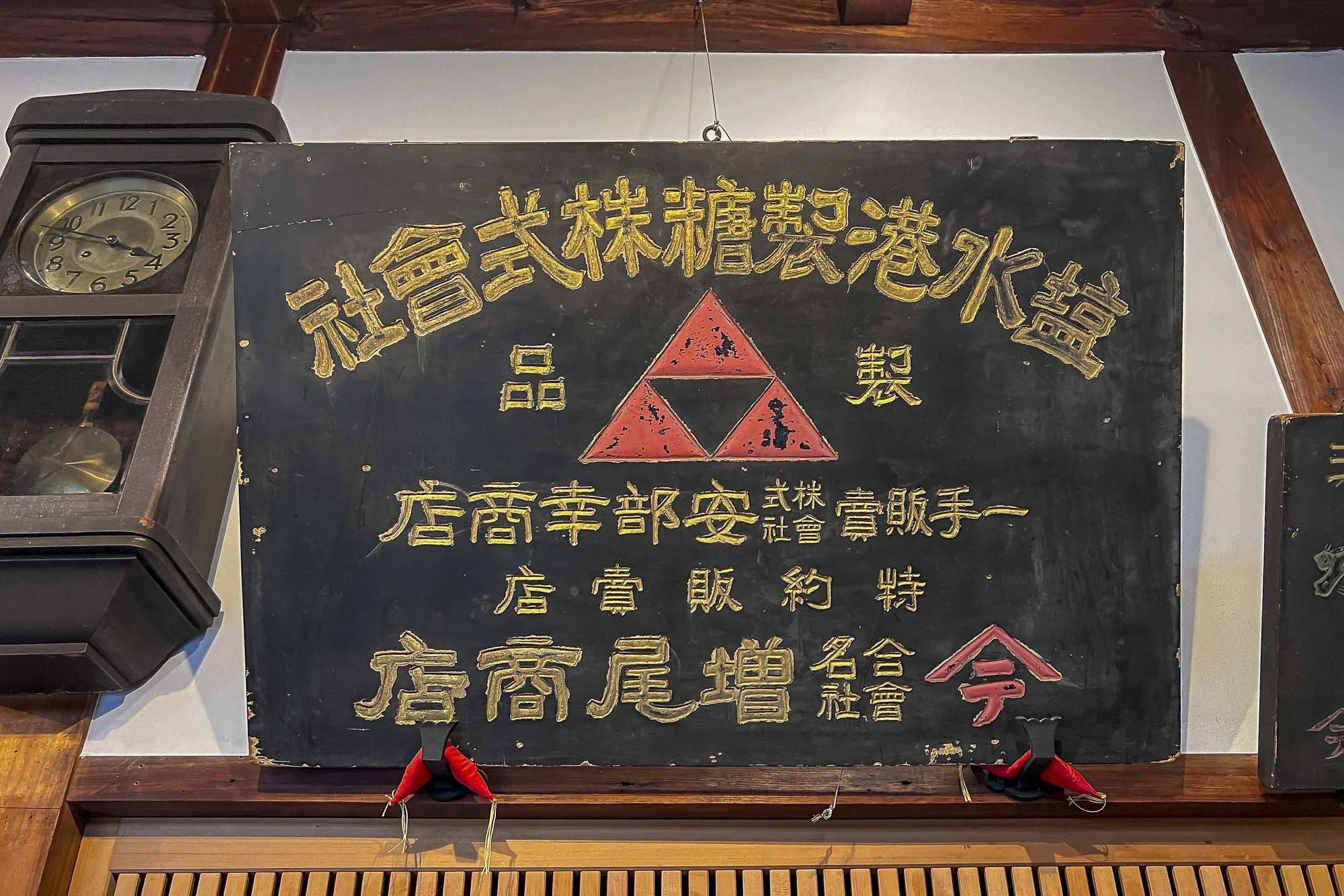Blackboard with yellow and red Chinese characters and symbols, including a red triangle with black details, hanging on a wall inside a building.
